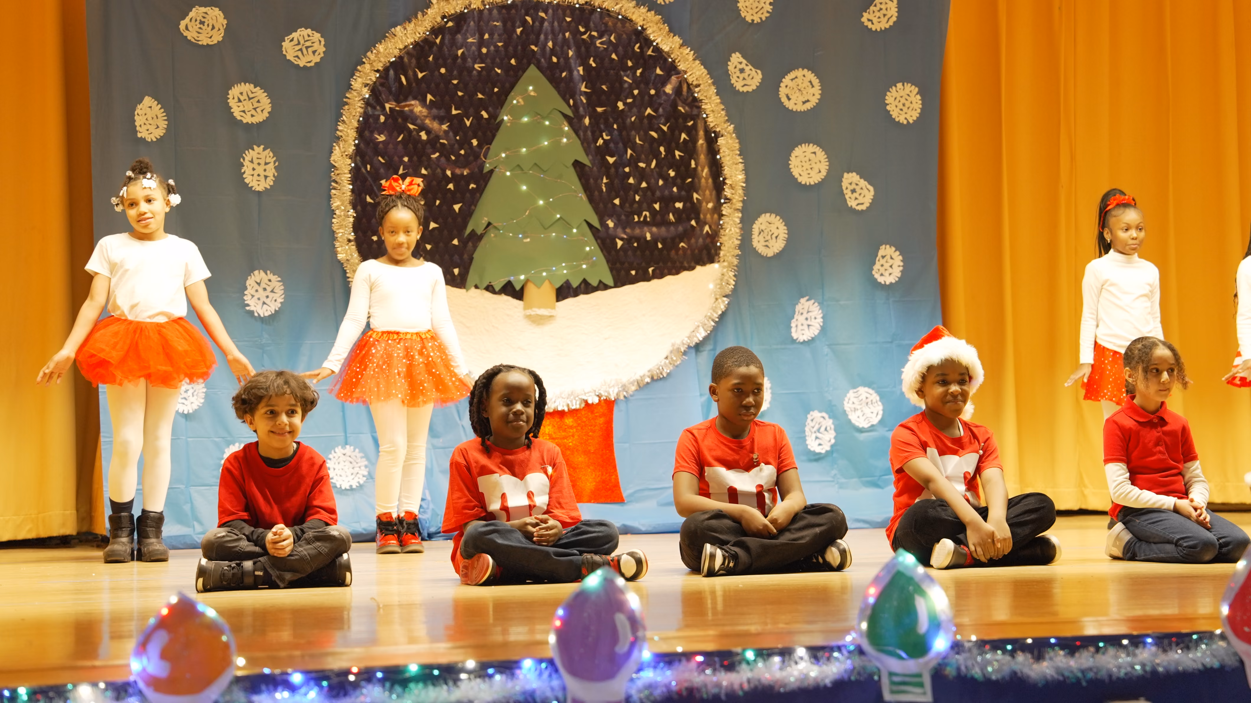 Students performing in a holiday stage show with Christmas backdrop