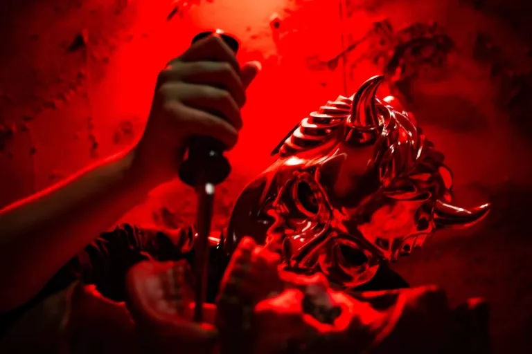A person holding a knife in front of a red light.