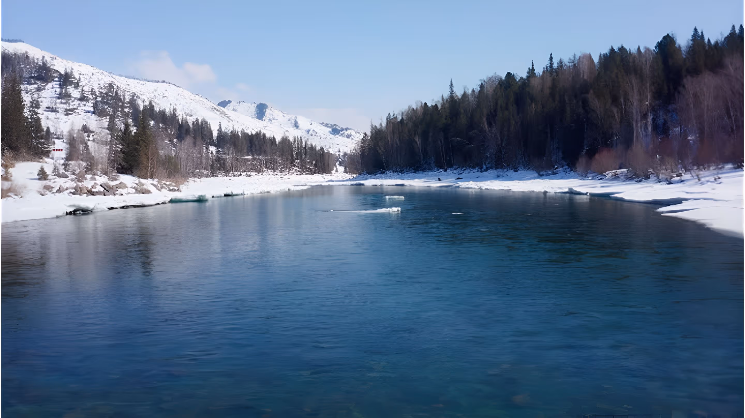 A body of water surrounded by snow covered mountains.