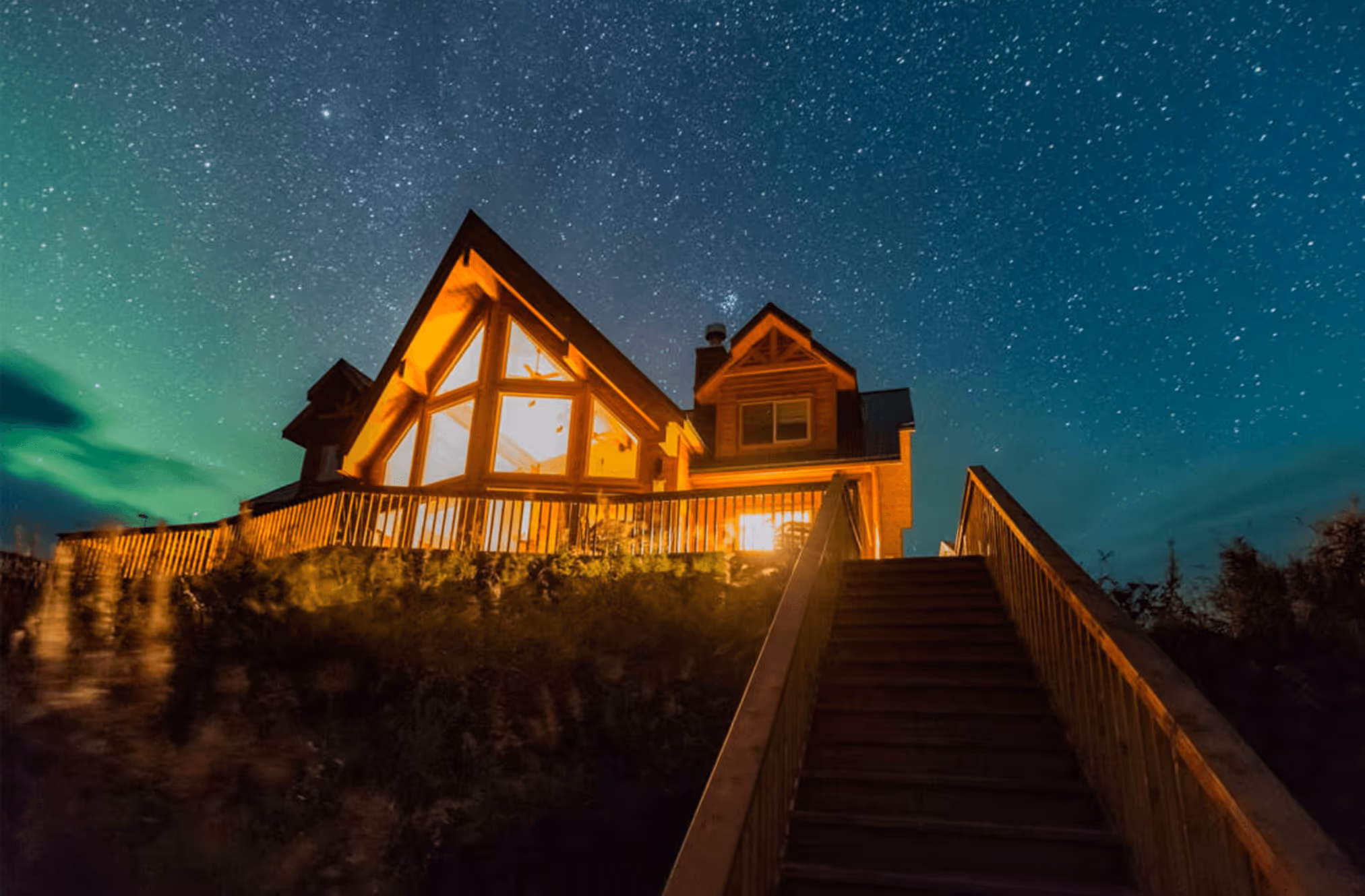 A house is lit up at night under the stars.