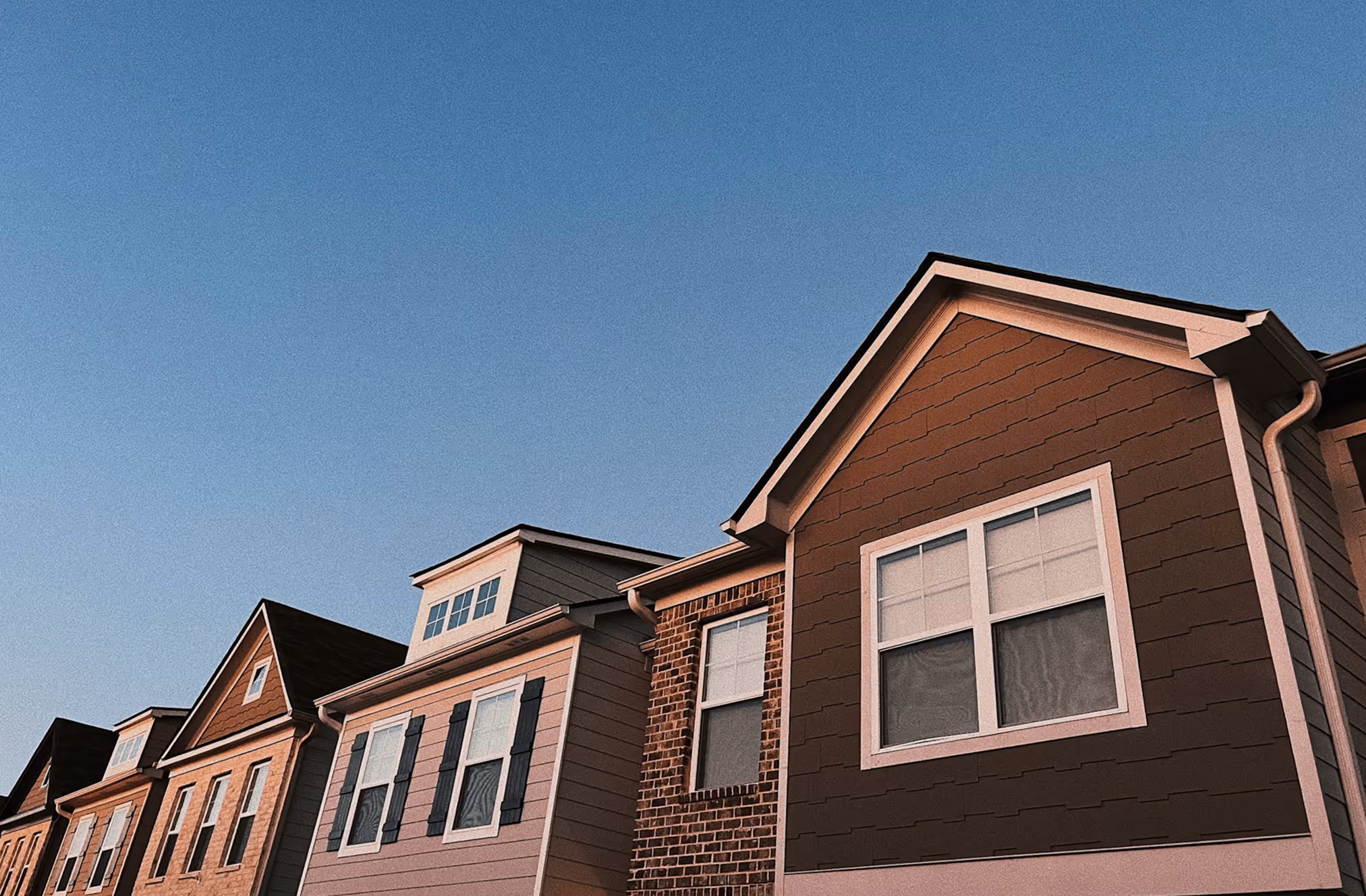 A row of houses with a clock on the side of the building.
