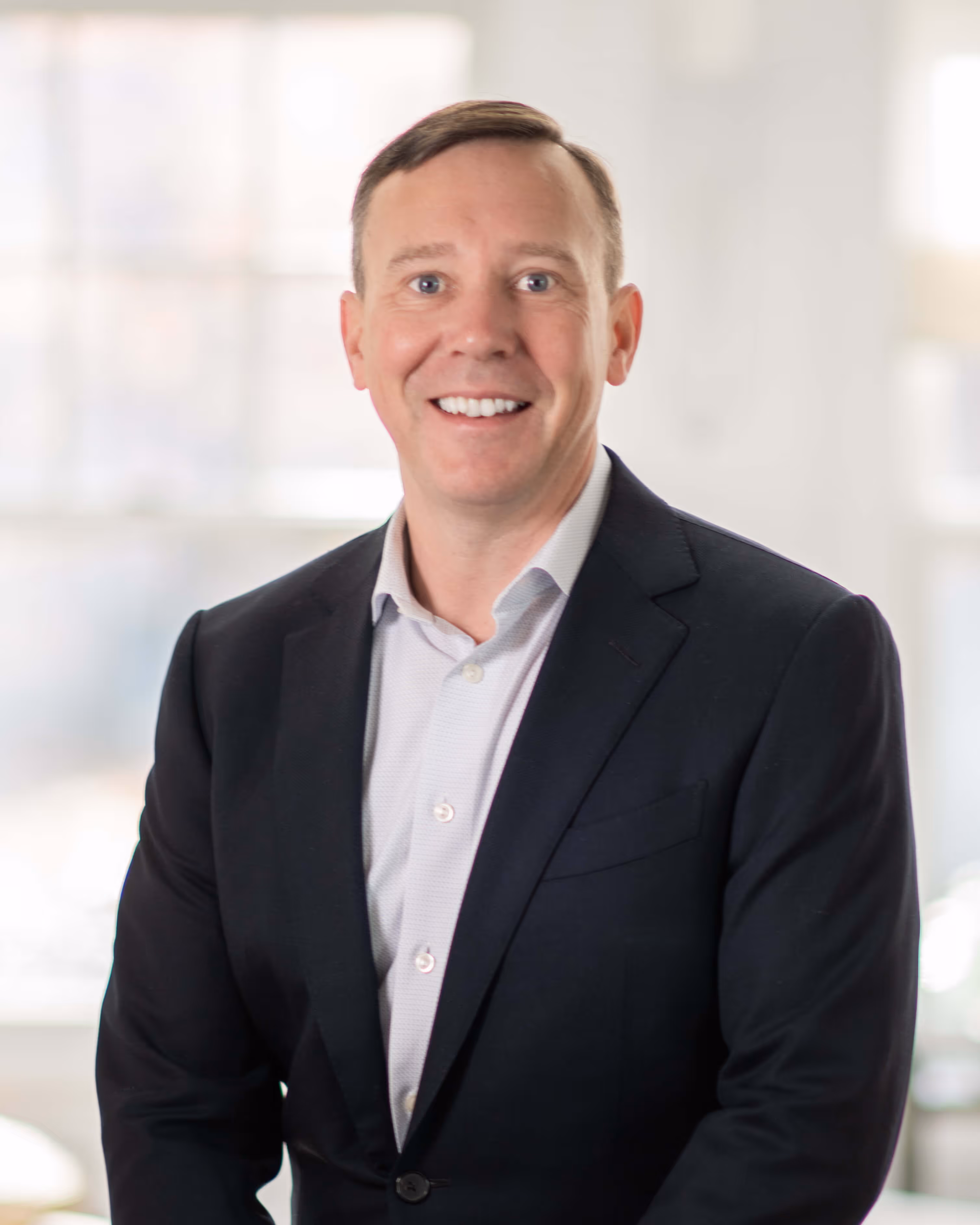 A man in a suit smiling for the camera.