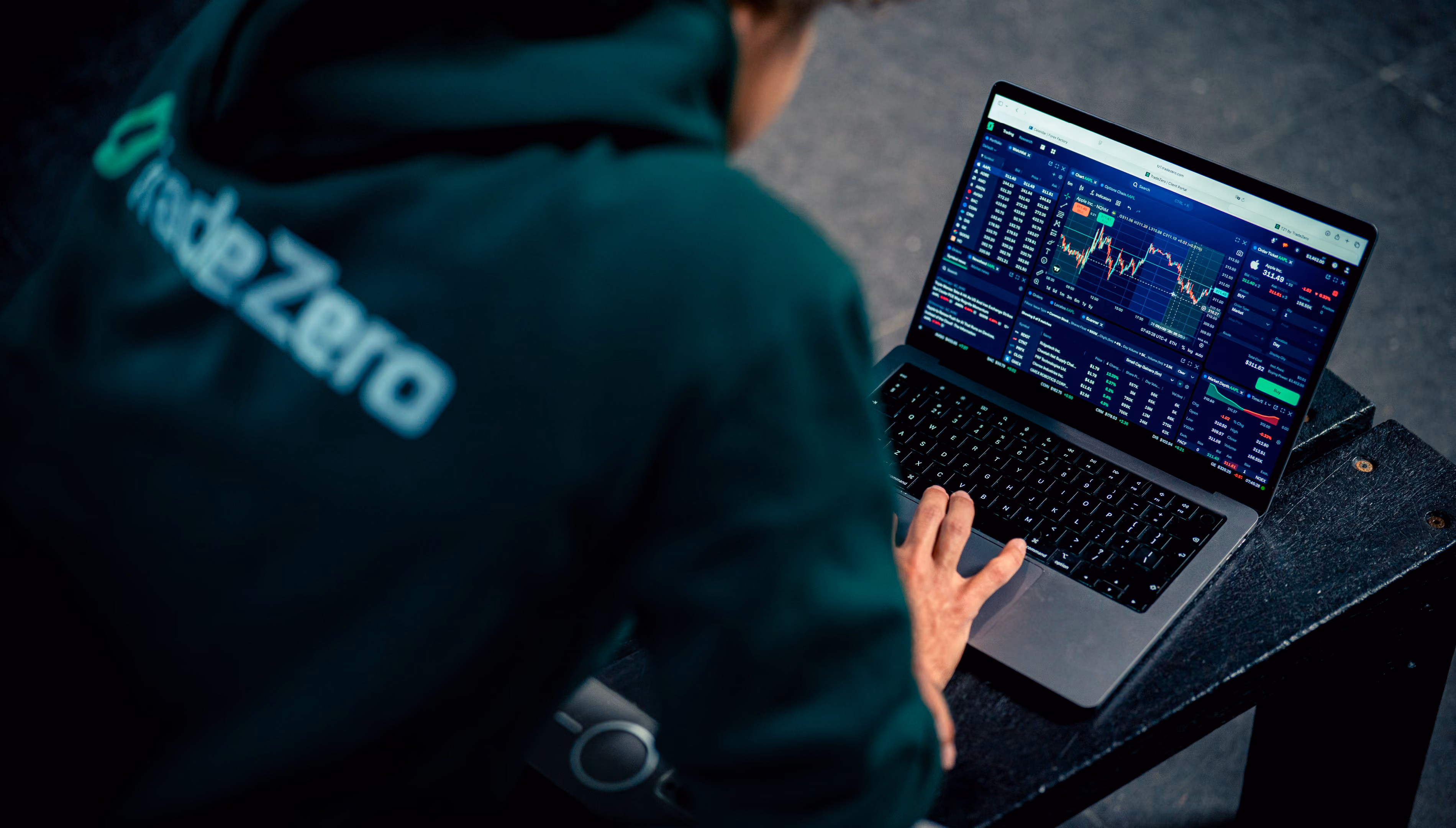 Persoon die op een laptop aandelen- en marktgegevens analyseert met TradeZero-kleding.