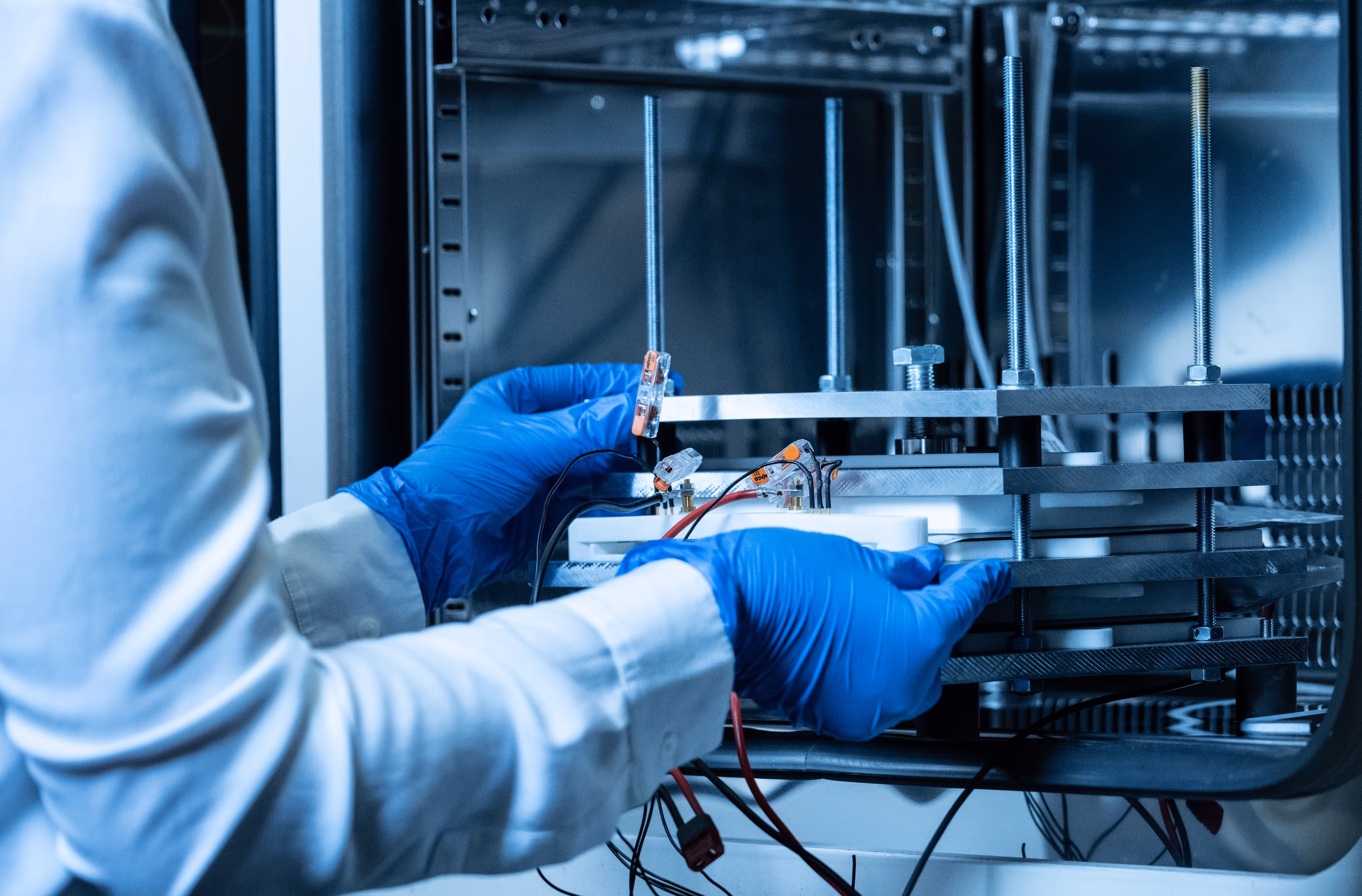 A person wearing blue gloves is holding a piece of electronic equipment.