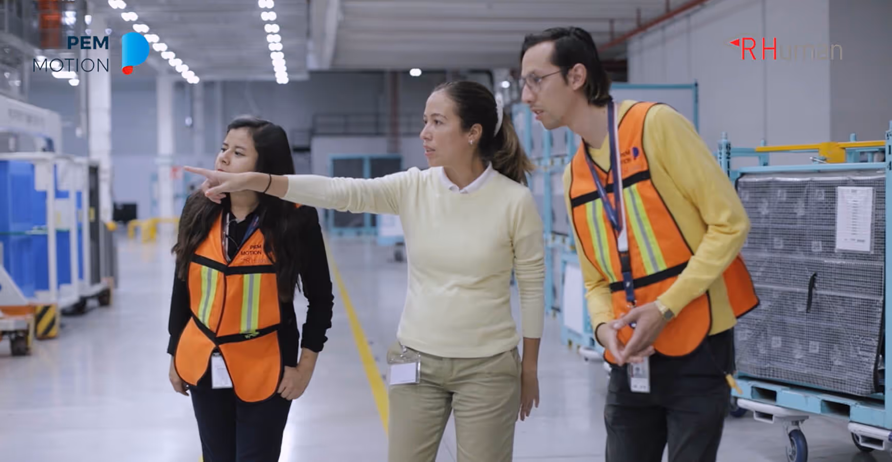Three people wearing safety vests are pointing at something.