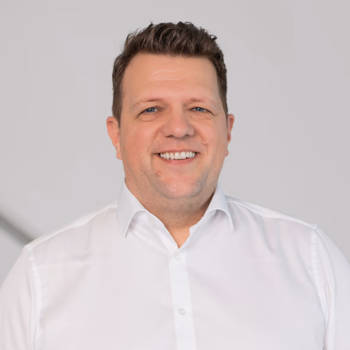 Ein Mann mit einem weißen Hemd und einem Lächeln.
