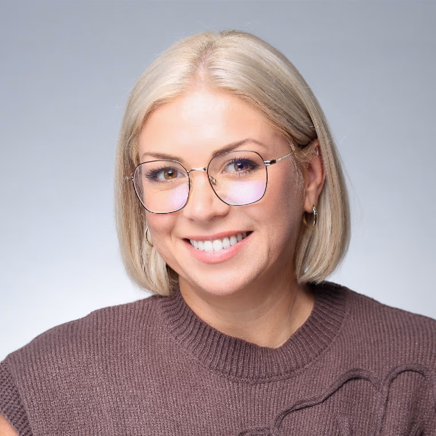 Eine Frau mit Brille und einem braunen Pullover.