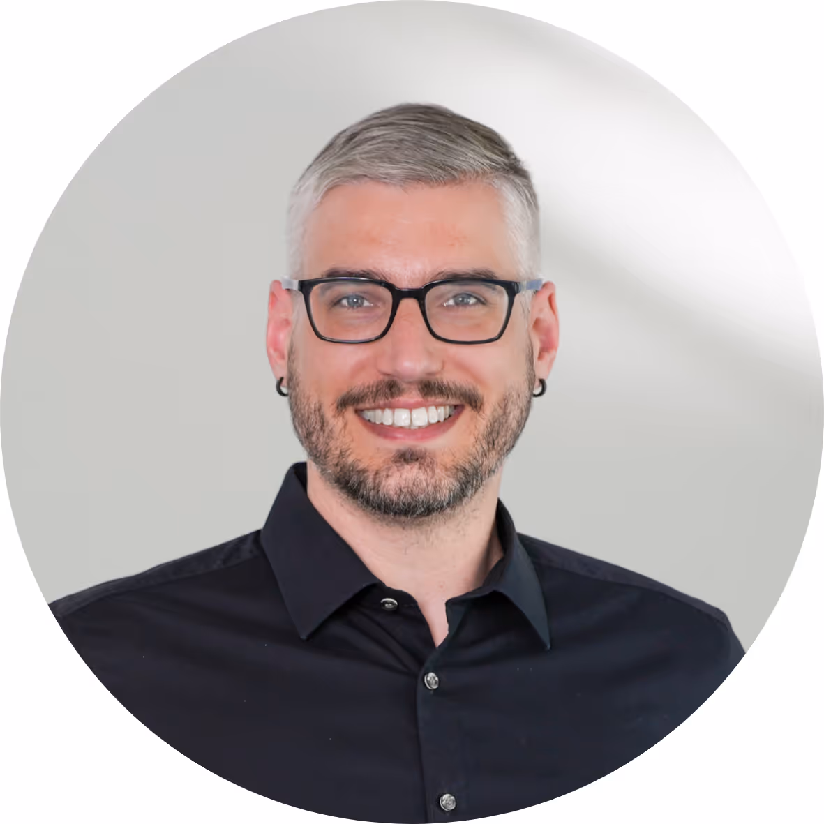 Ein Mann mit Brille und einem schwarzen Hemd.