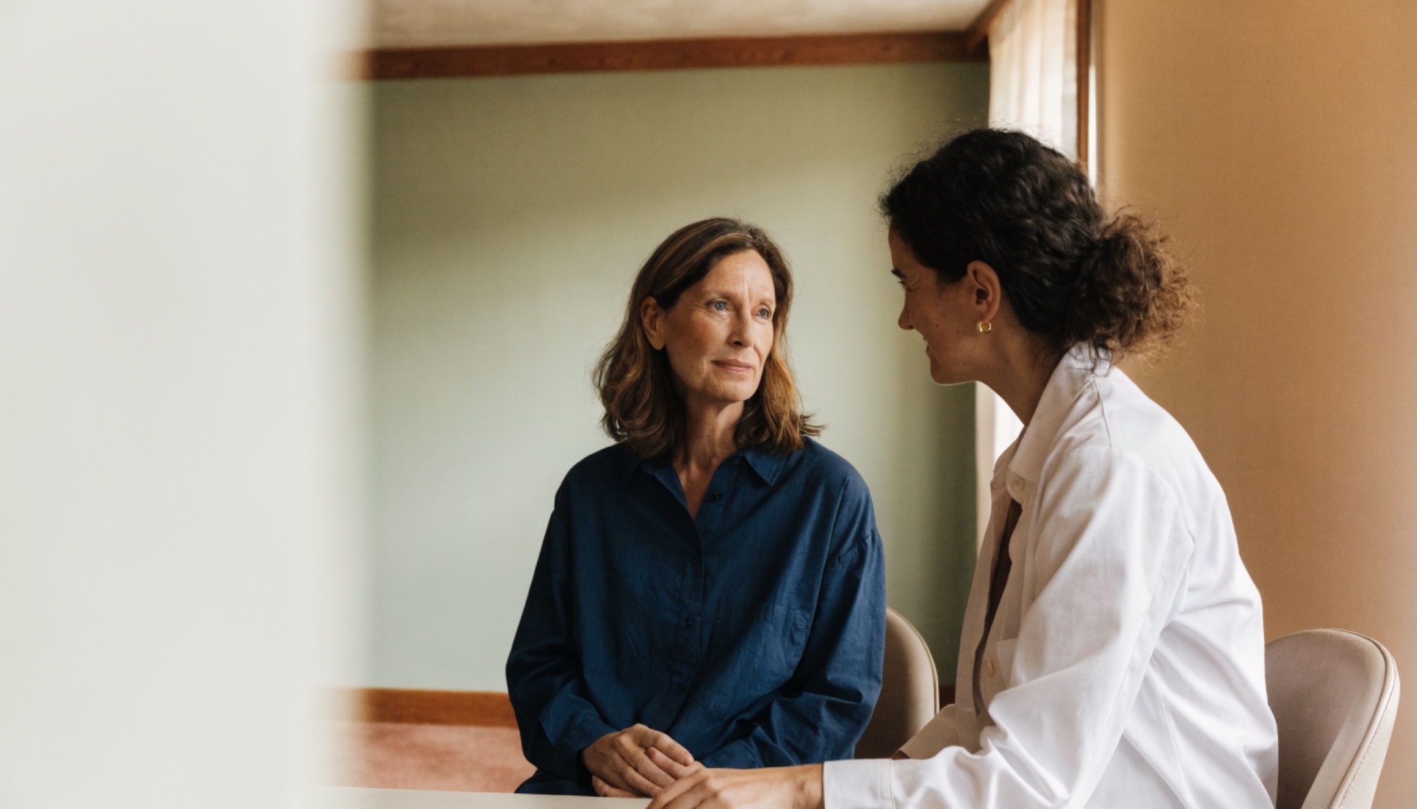 Vrouw in gesprek met een arts in een lichte spreekkamer