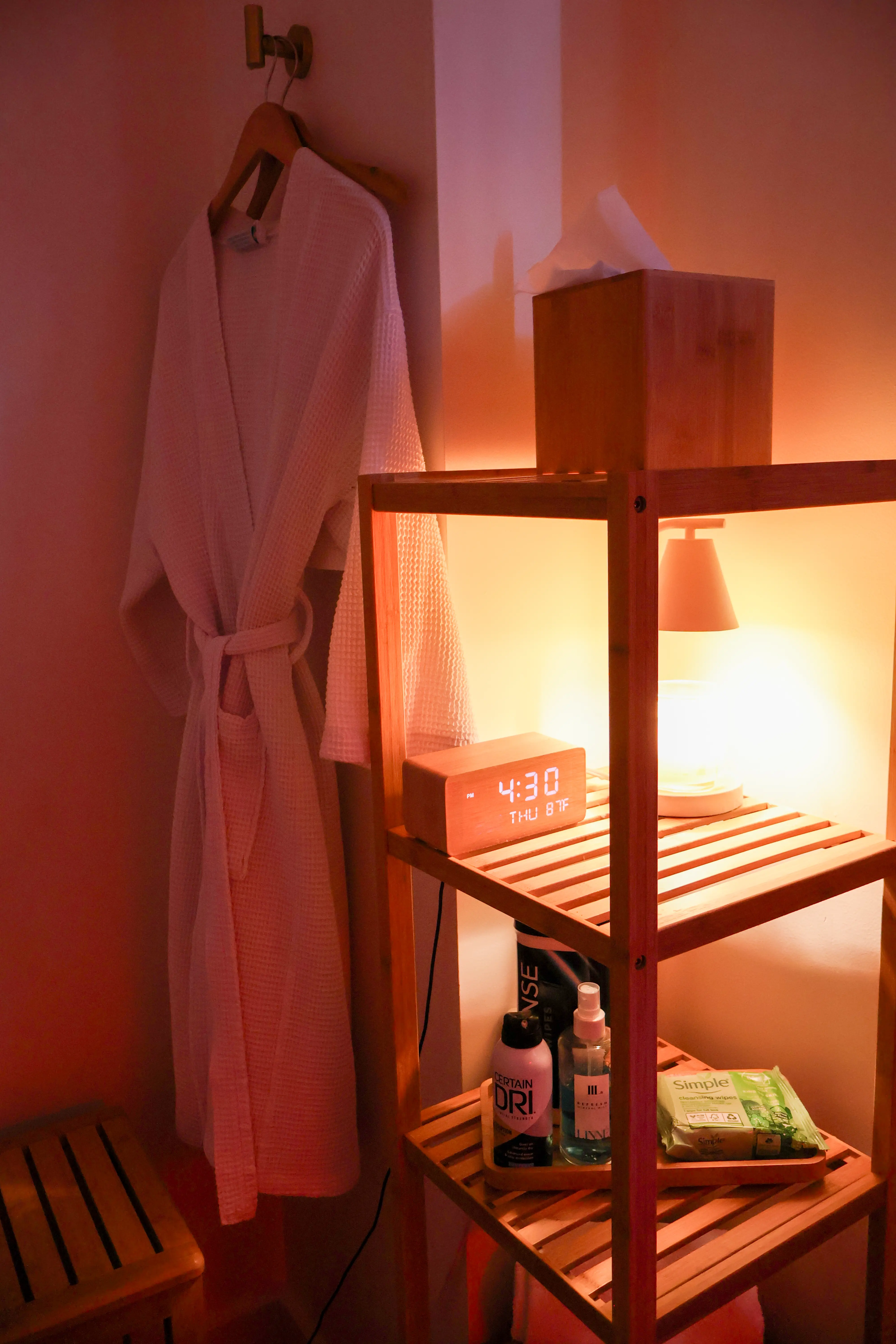 A robe hanging on a rack next to a night stand.