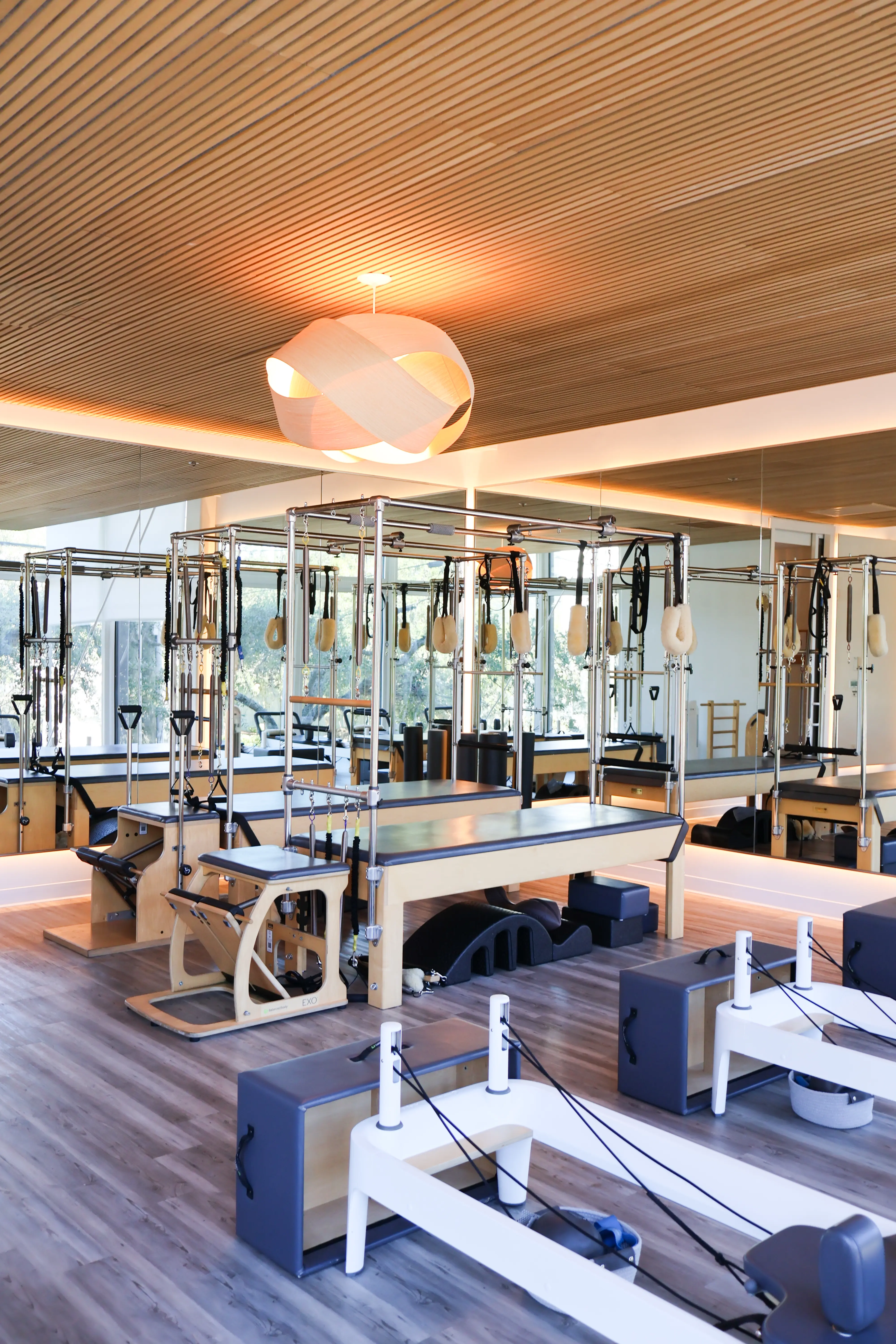A gym filled with machines and equipment on a hard wood floor.