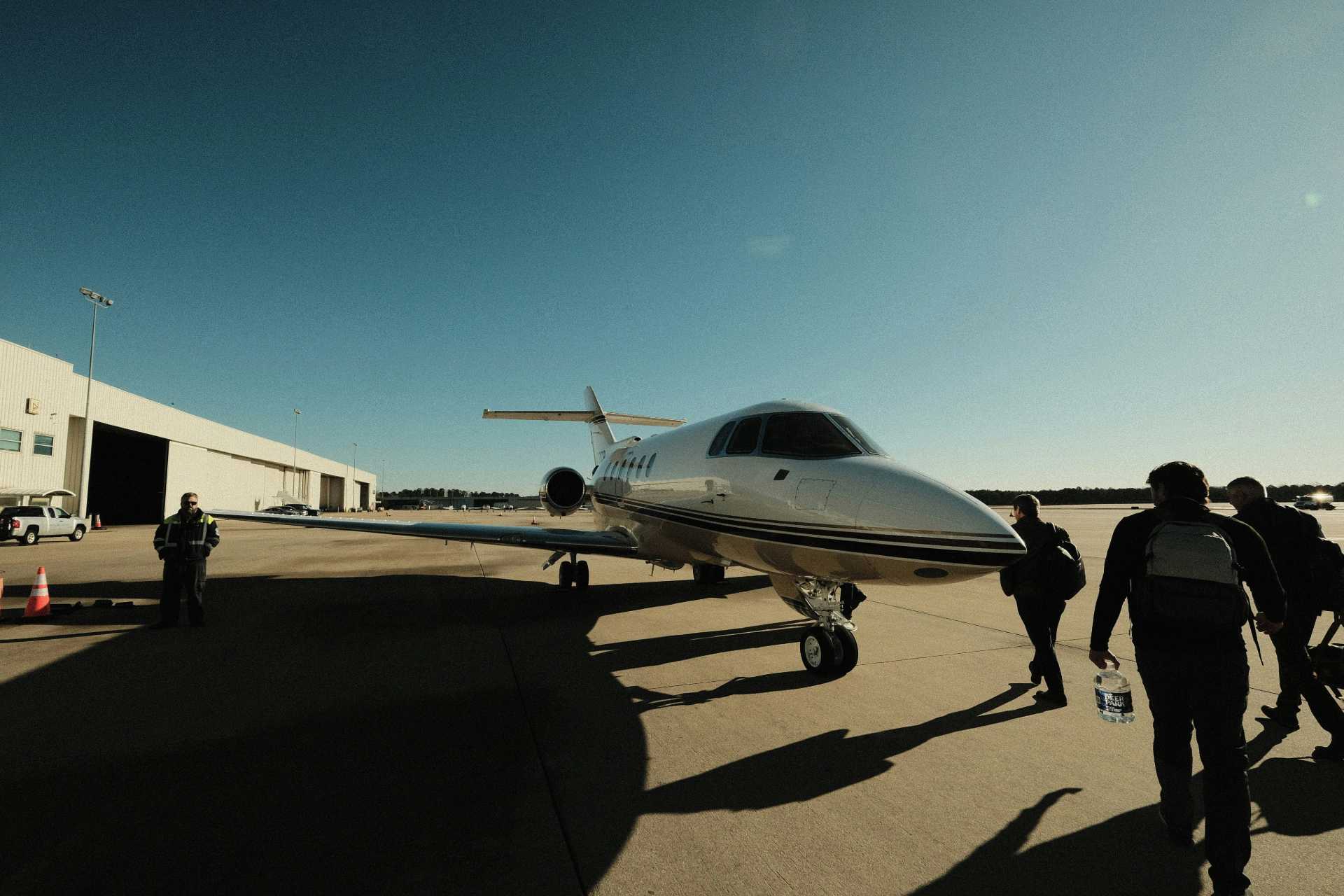 A private jet on the ground with people walking towards it