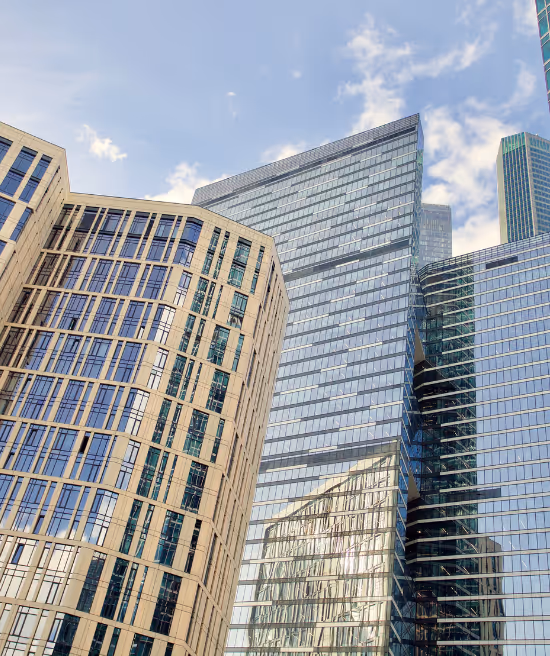 Modern high-rise buildings with glass and concrete facades under a partly cloudy sky.