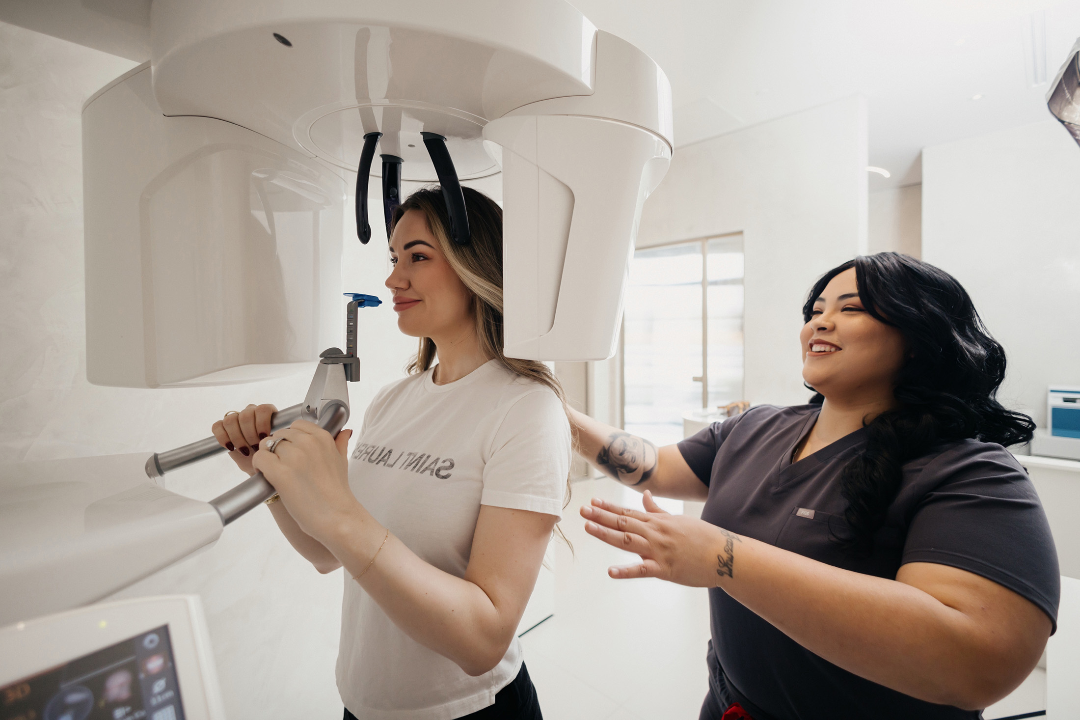 A dental professional assists a patient undergoing a dental X-ray scan using a large panoramic X-ray machine. — Clio Dental S