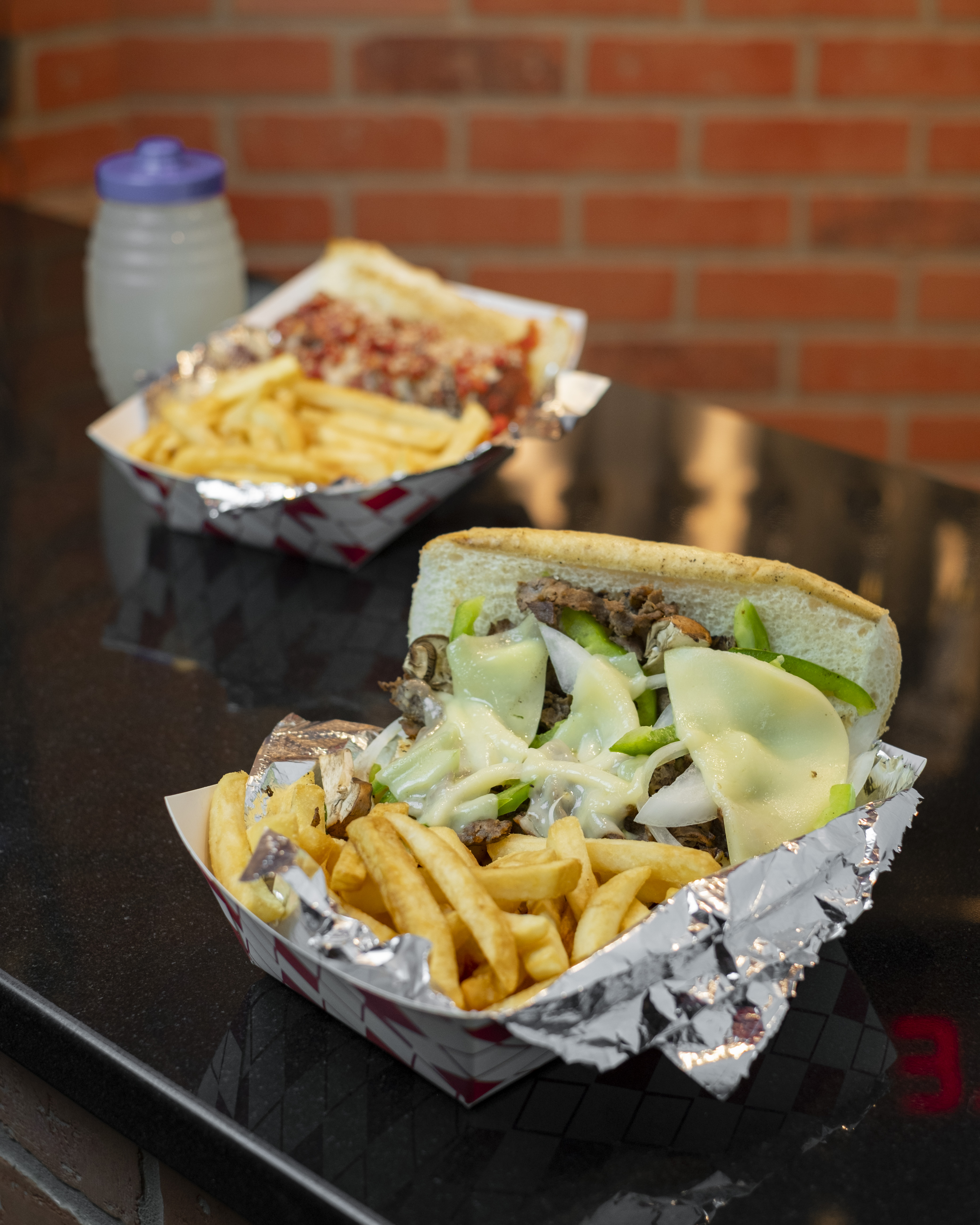 Burger with fried fries on black plate with sauce on the side