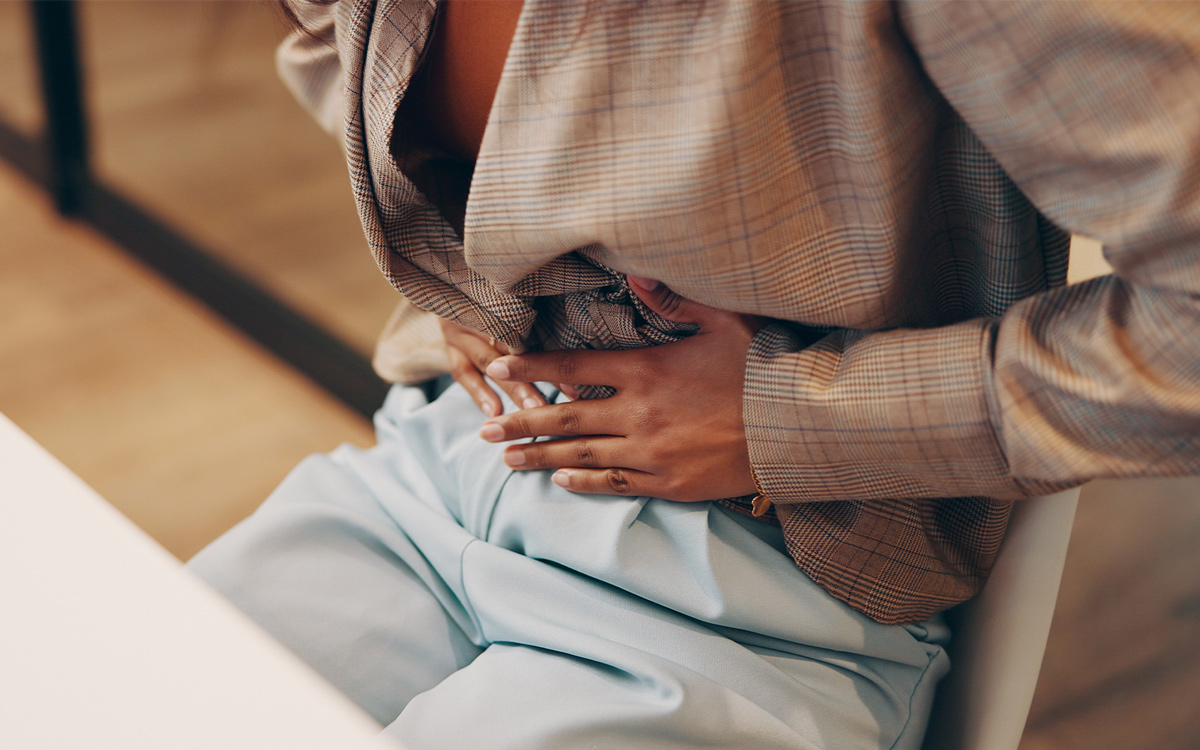 A woman holds her abdomen due to pain and inflammation of endometriosis