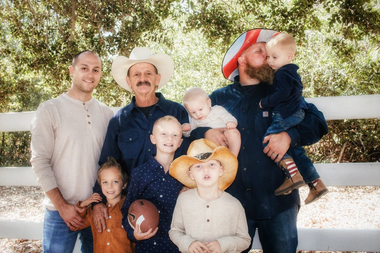 A joyful family gathering outdoors with children and adults, featuring cowboy hats and a football.
