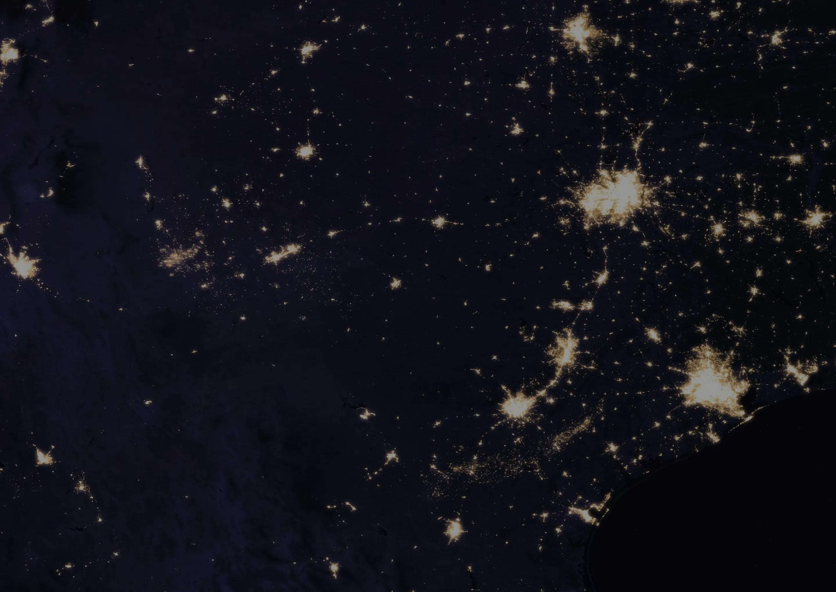 Satellite view of Texas at night showing illuminated cities and road networks against the dark landscape.