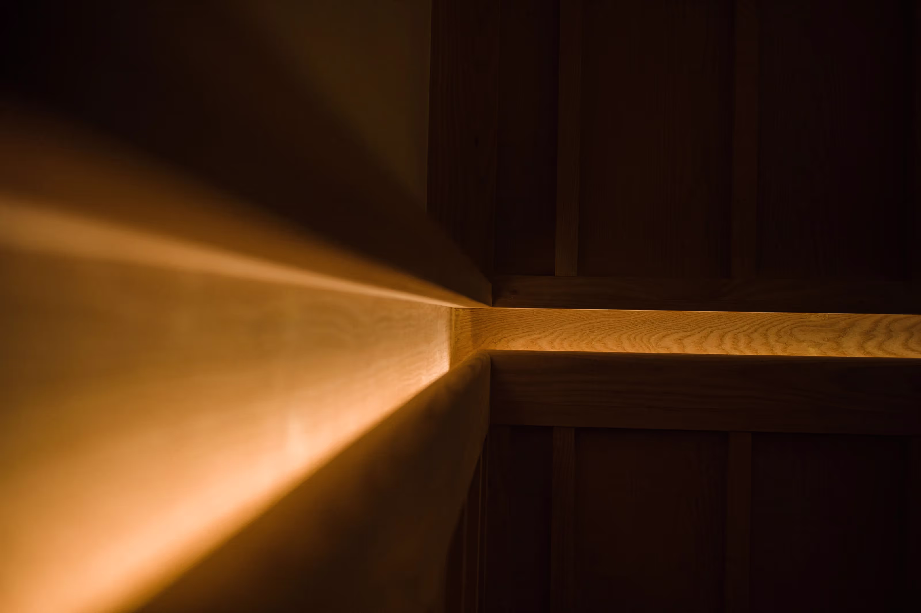 Warm light glowing along the edges of wooden panels at a corner.