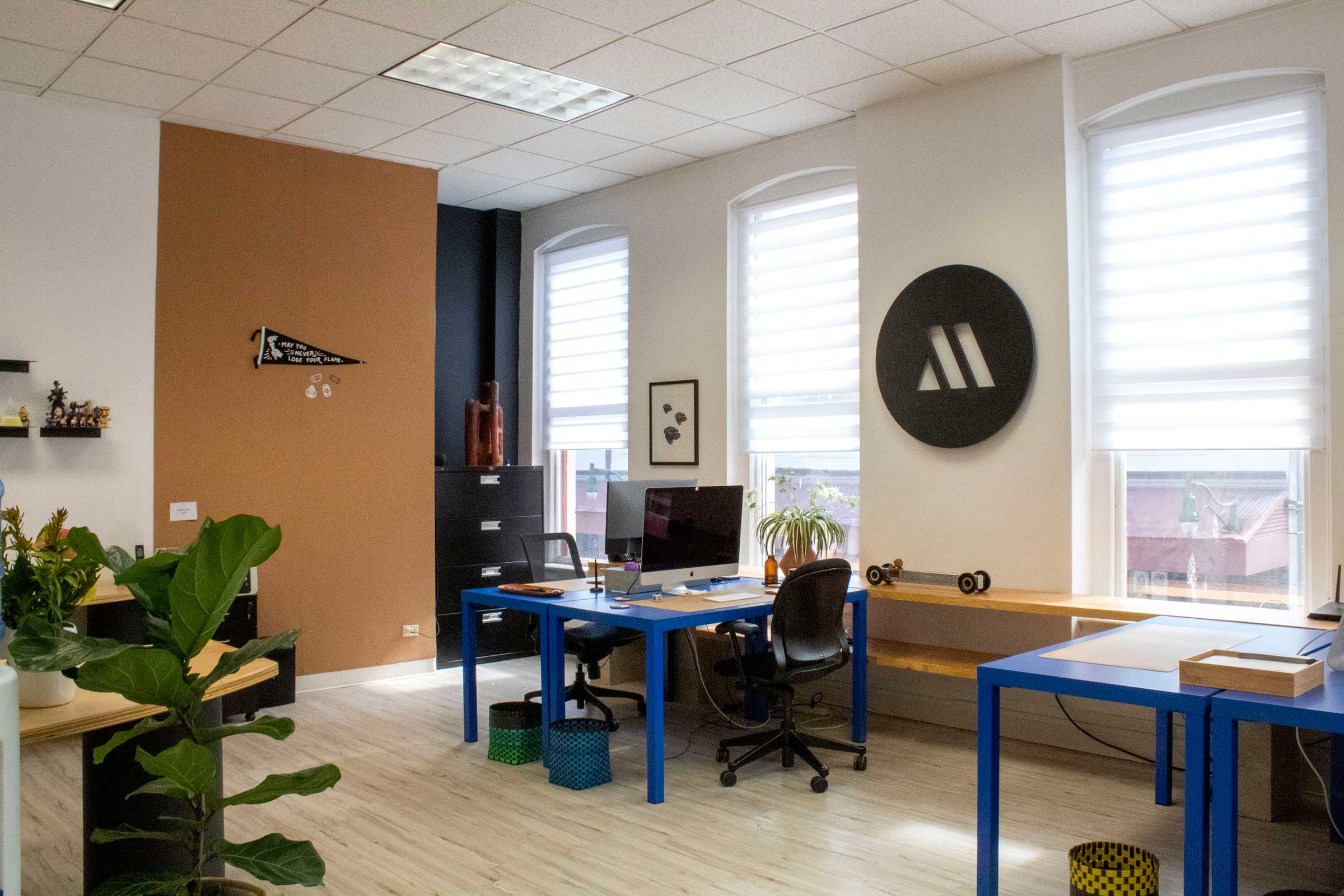 Photo of the middle mgmt office with blue desks and logo attached to the wall