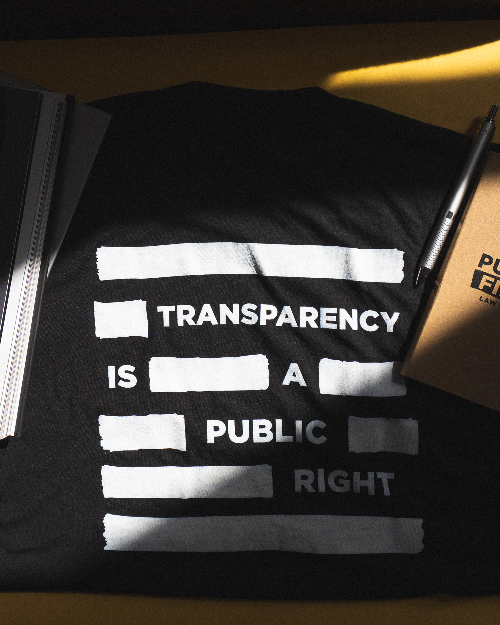 Black fabric with white text stating transparency is a public right, with some words redacted.