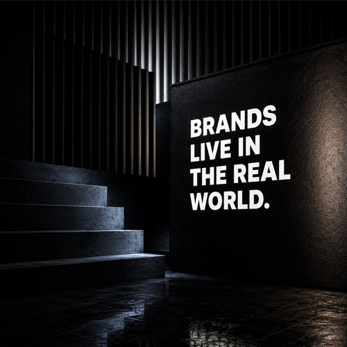 Dark modern space with stairs and a lit wall reading, "BRANDS LIVE IN THE REAL WORLD."