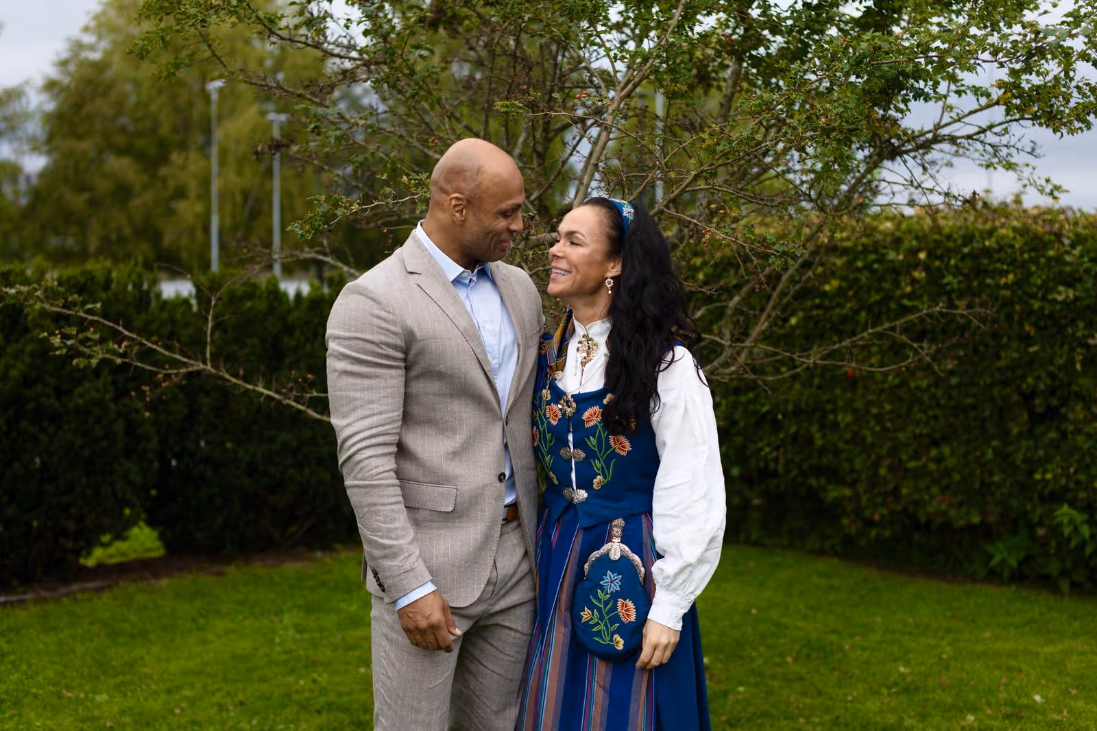 Tonje i blå bunad smilende sammen med en mann i dress på 17. mai