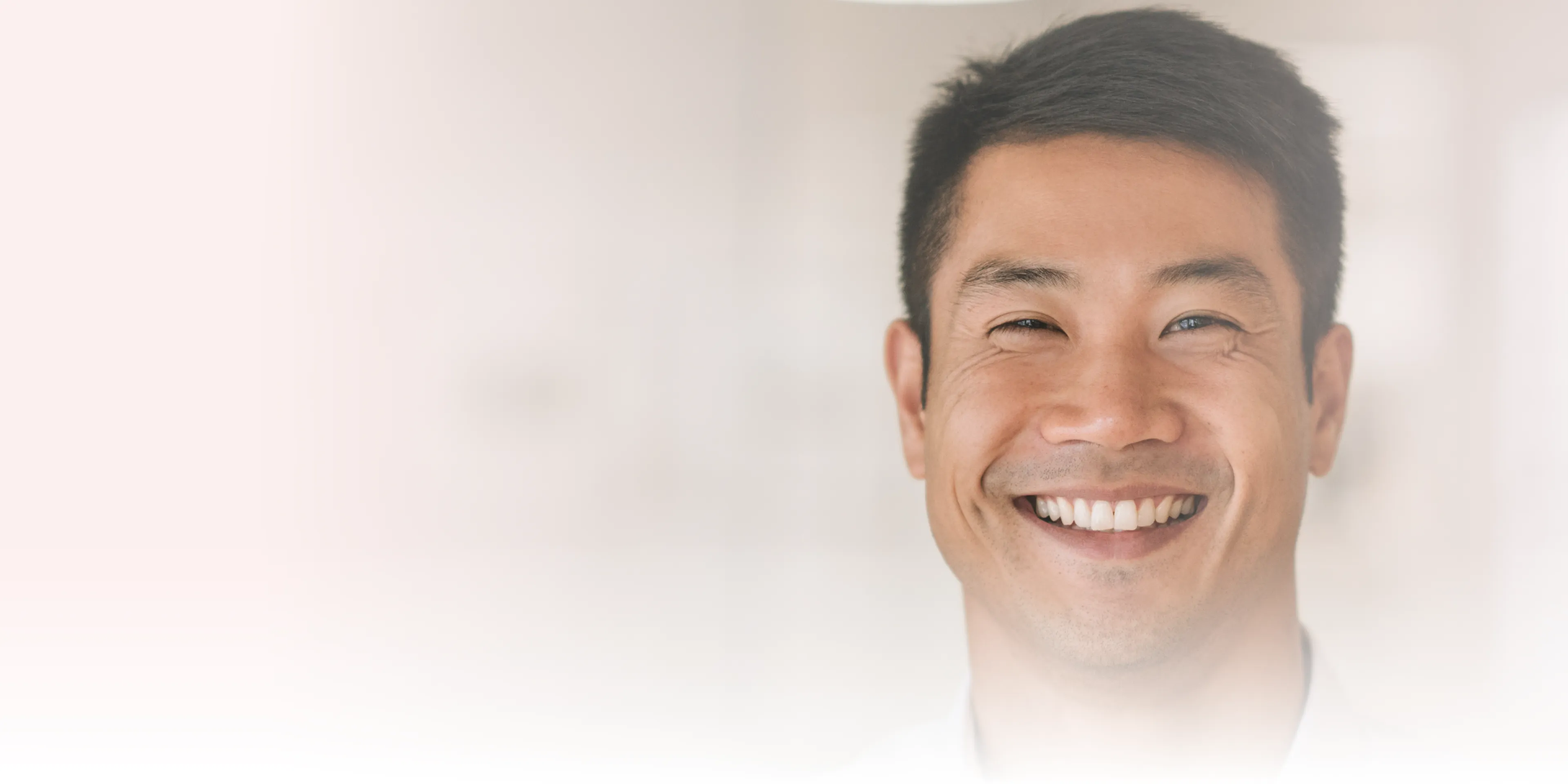 Smiling person looking directly at the camera against a simple, light background.