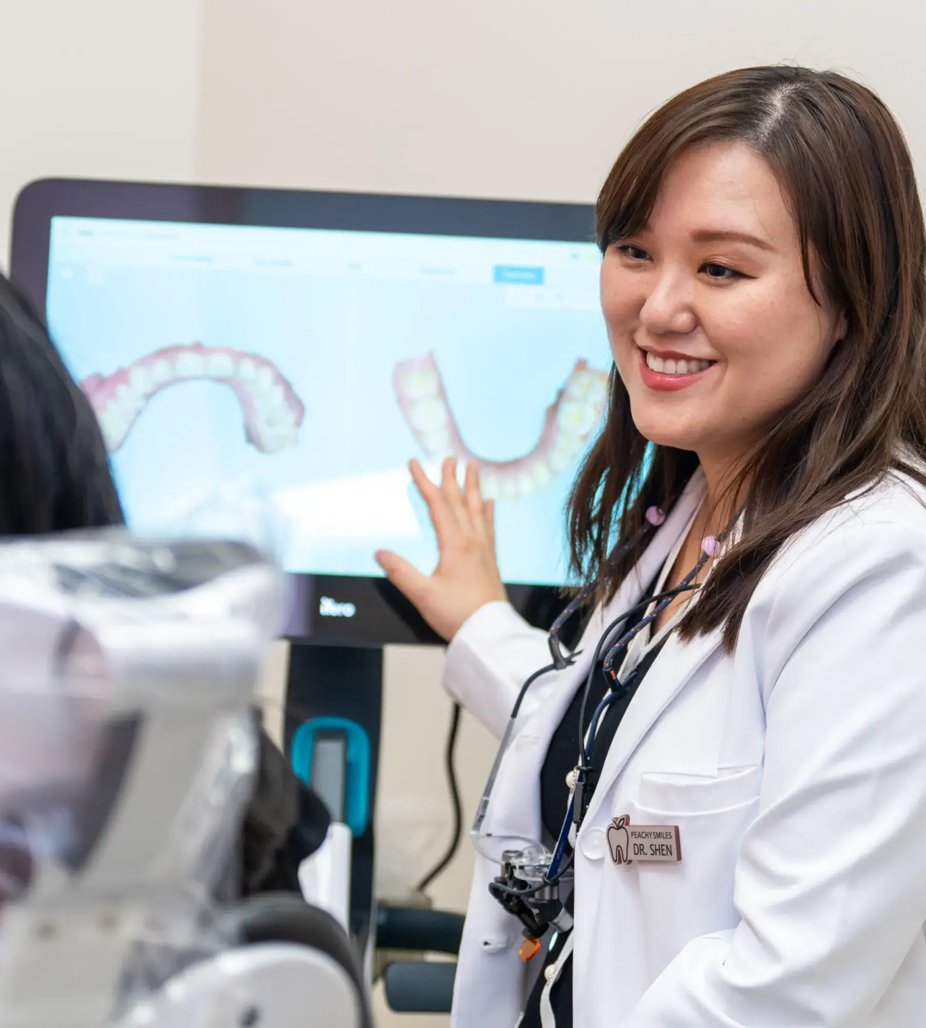 A dentist standing in front of a computer screen.