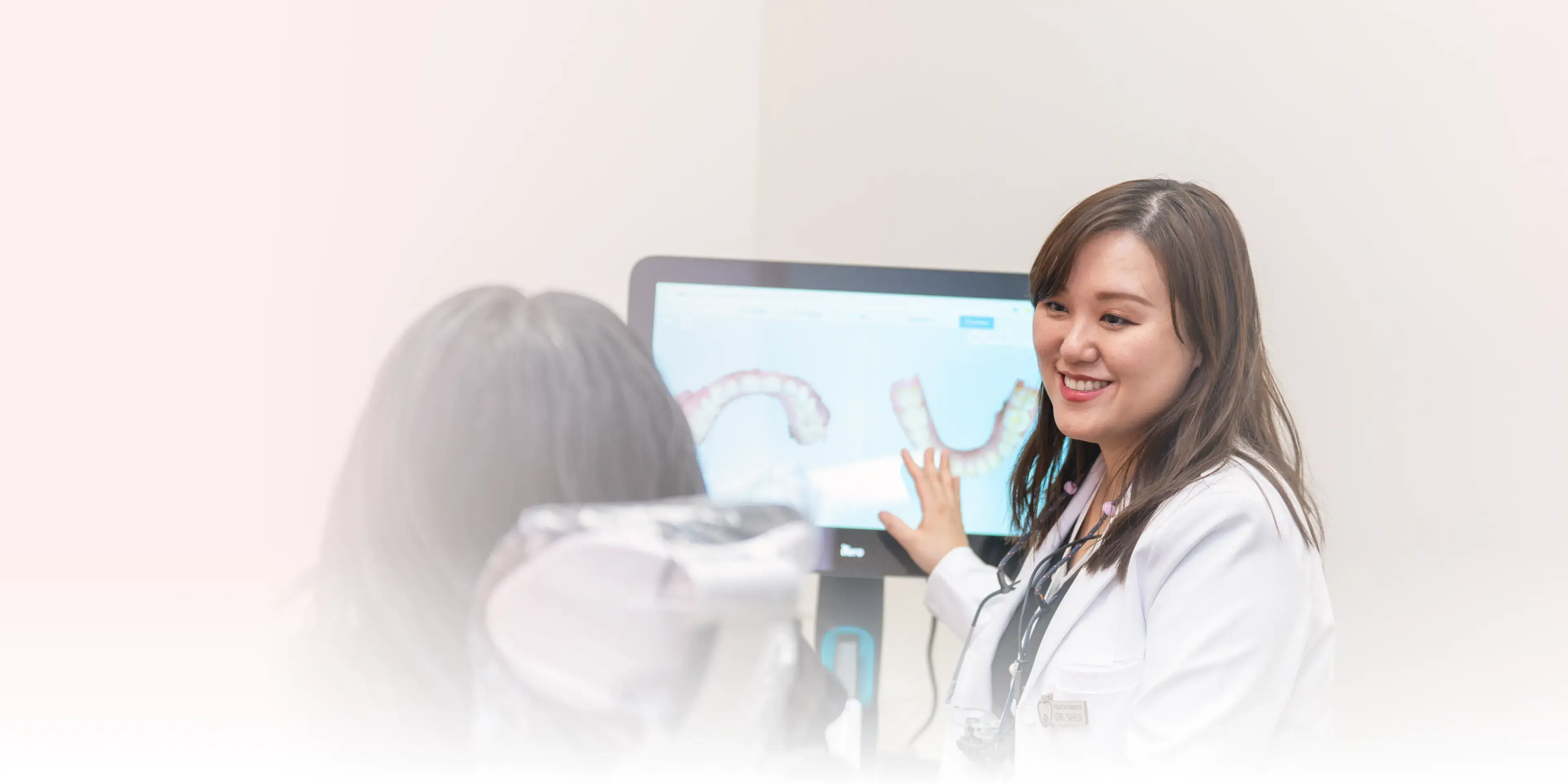 A dentist standing in front of a computer screen.