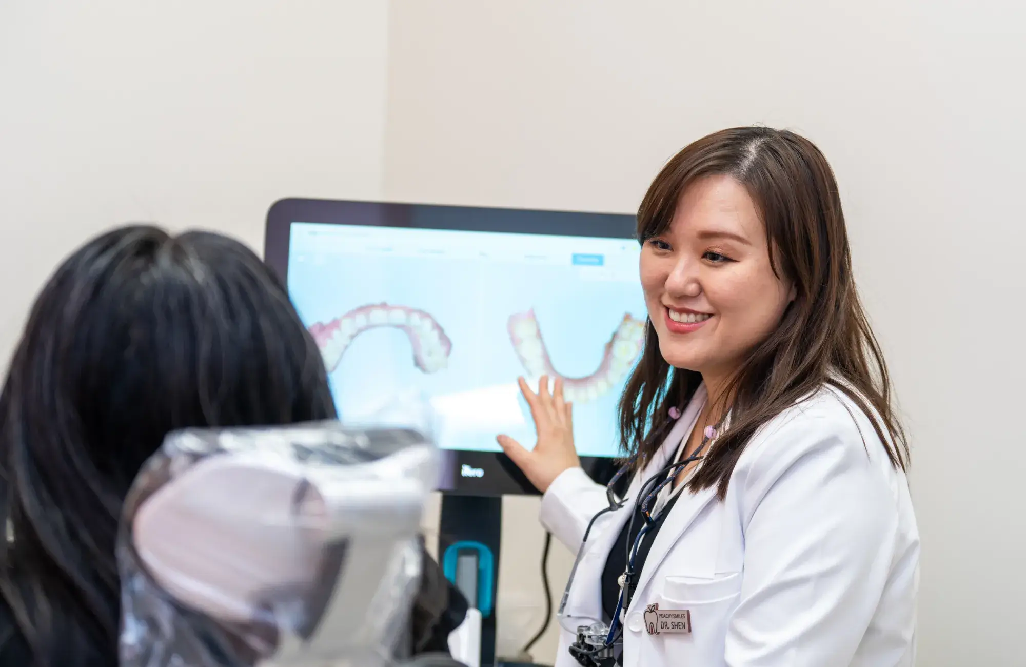 A dentist standing in front of a computer screen.