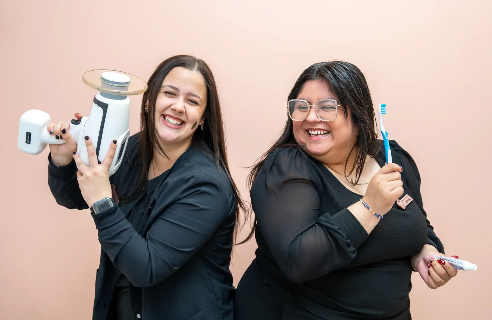A couple of women standing next to each other holding toothbrushes.