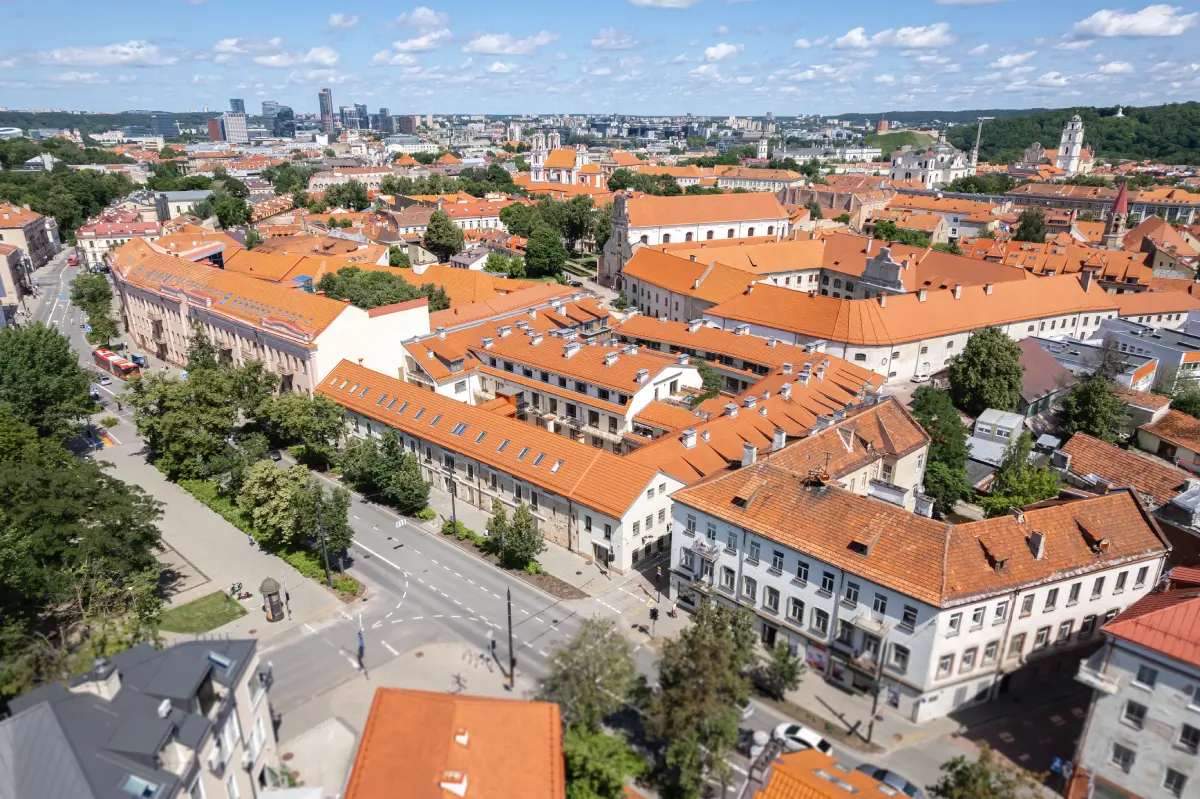 Vilniaus senamiestis su oranžinės spalvos stogais ir miesto panorama po saulėtu dangumi.