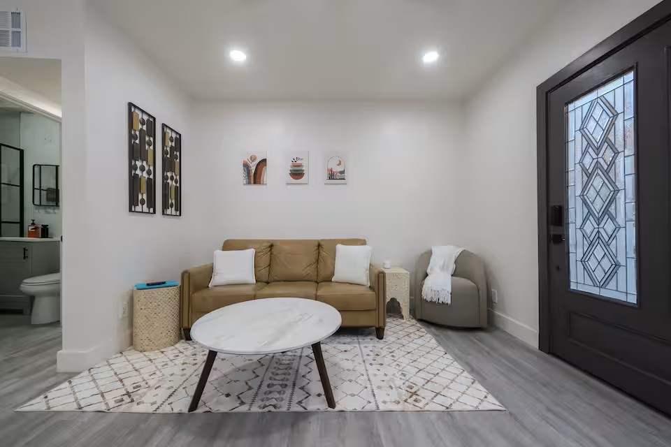 Modern living room with neutral furniture, white walls, and soft recessed lighting in a Tucson vacation rental.