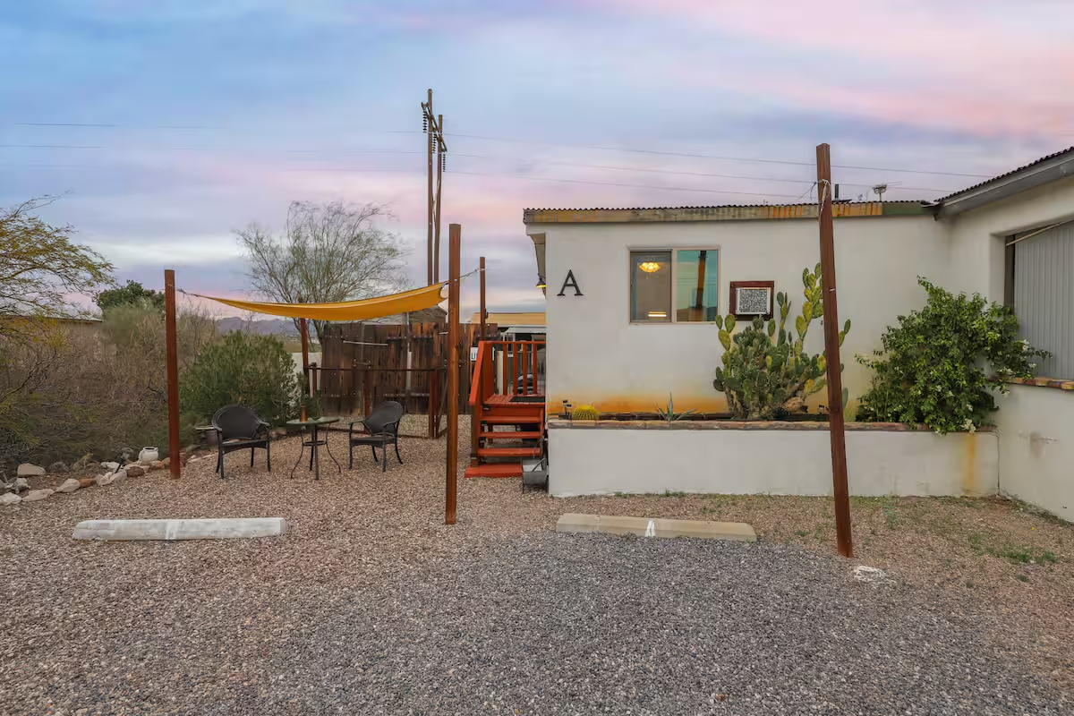 Cozy casita kitchenette and dining area with white cabinetry, small dining table, and colorful artwork and decor.