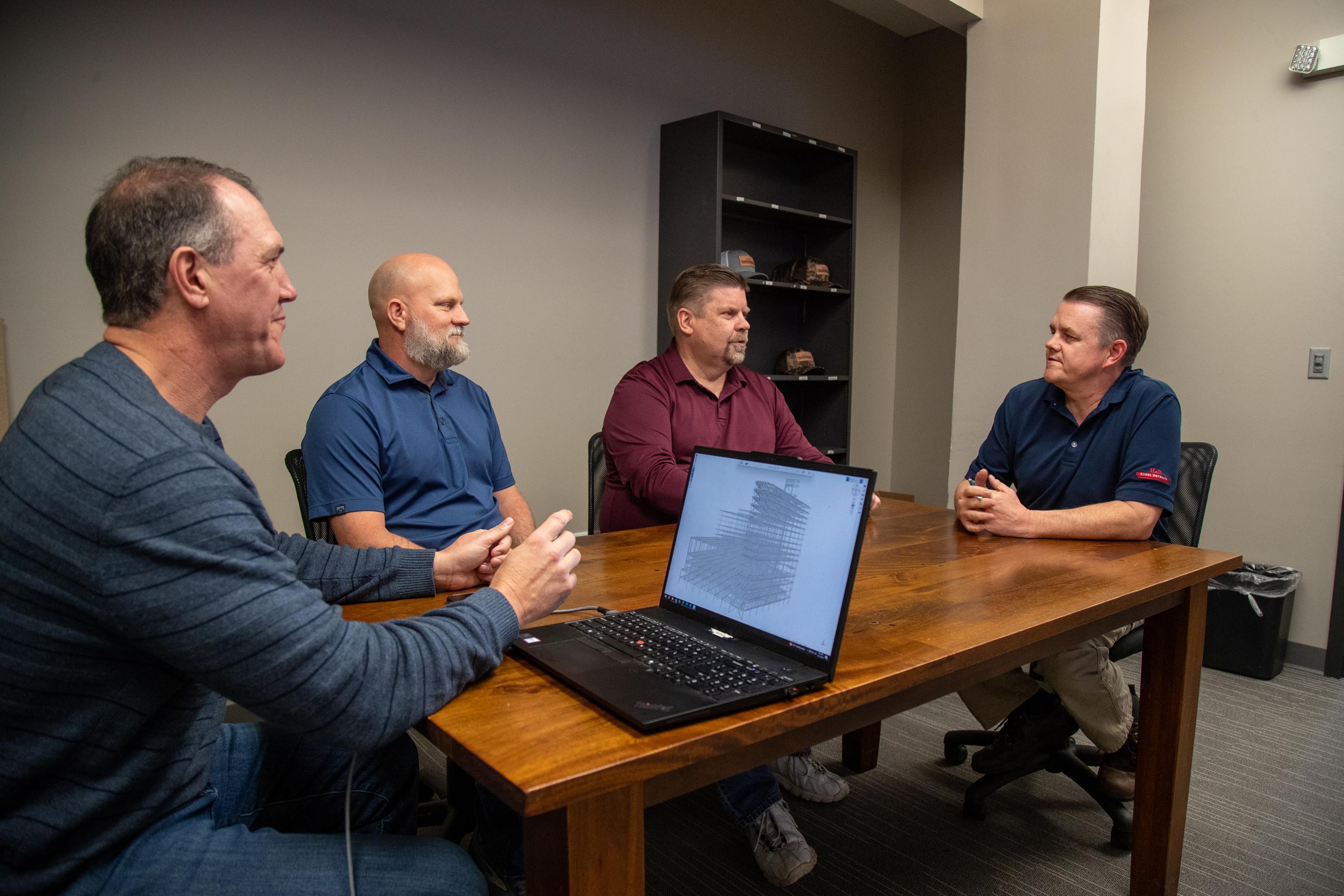 Four H&R Steel Detailing leaders talking around a conference table with a laptop open