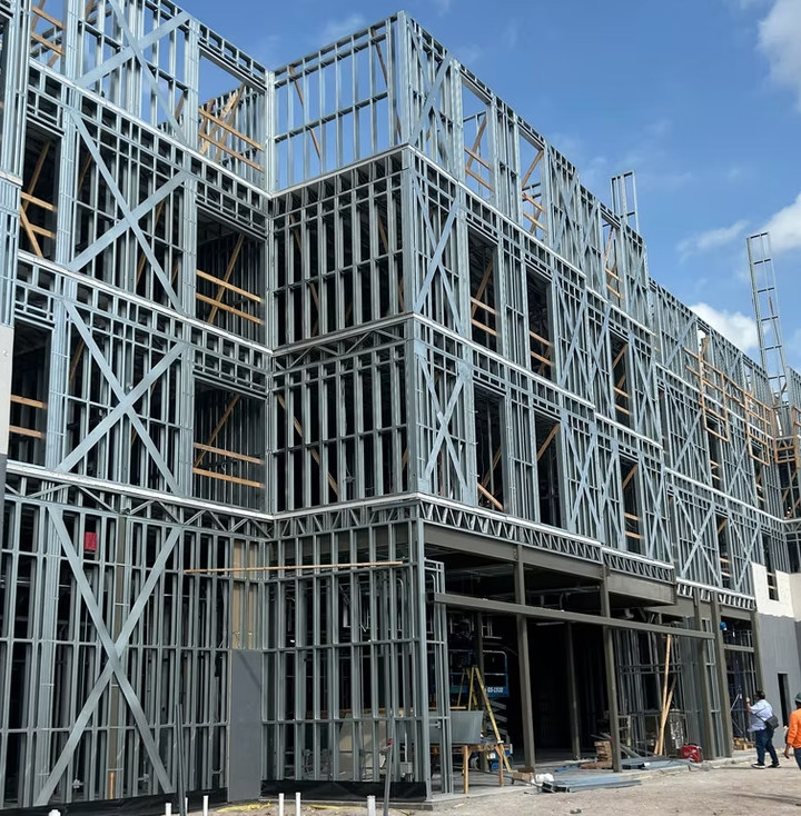 Cold-formed steel framing on a multi-story mixed-use building under construction, showing panelized steel wall assemblies and mid-rise structural layout.