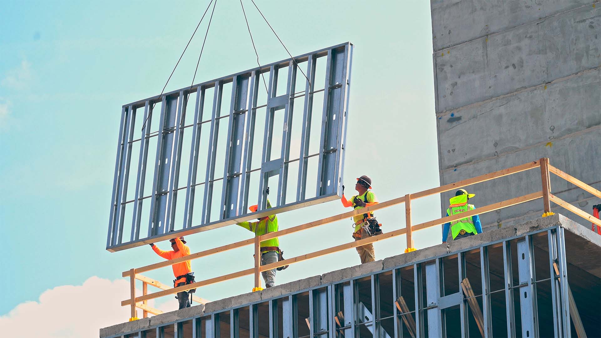 Panelized cold-formed steel wall panel being lifted and installed on a multi-story building