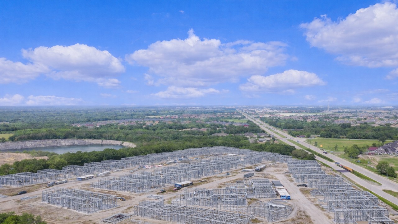 Aerial view of a built-to-rent subdivision under construction with extensive cold-formed steel (metal stud) framing across multiple buildings and site roads.