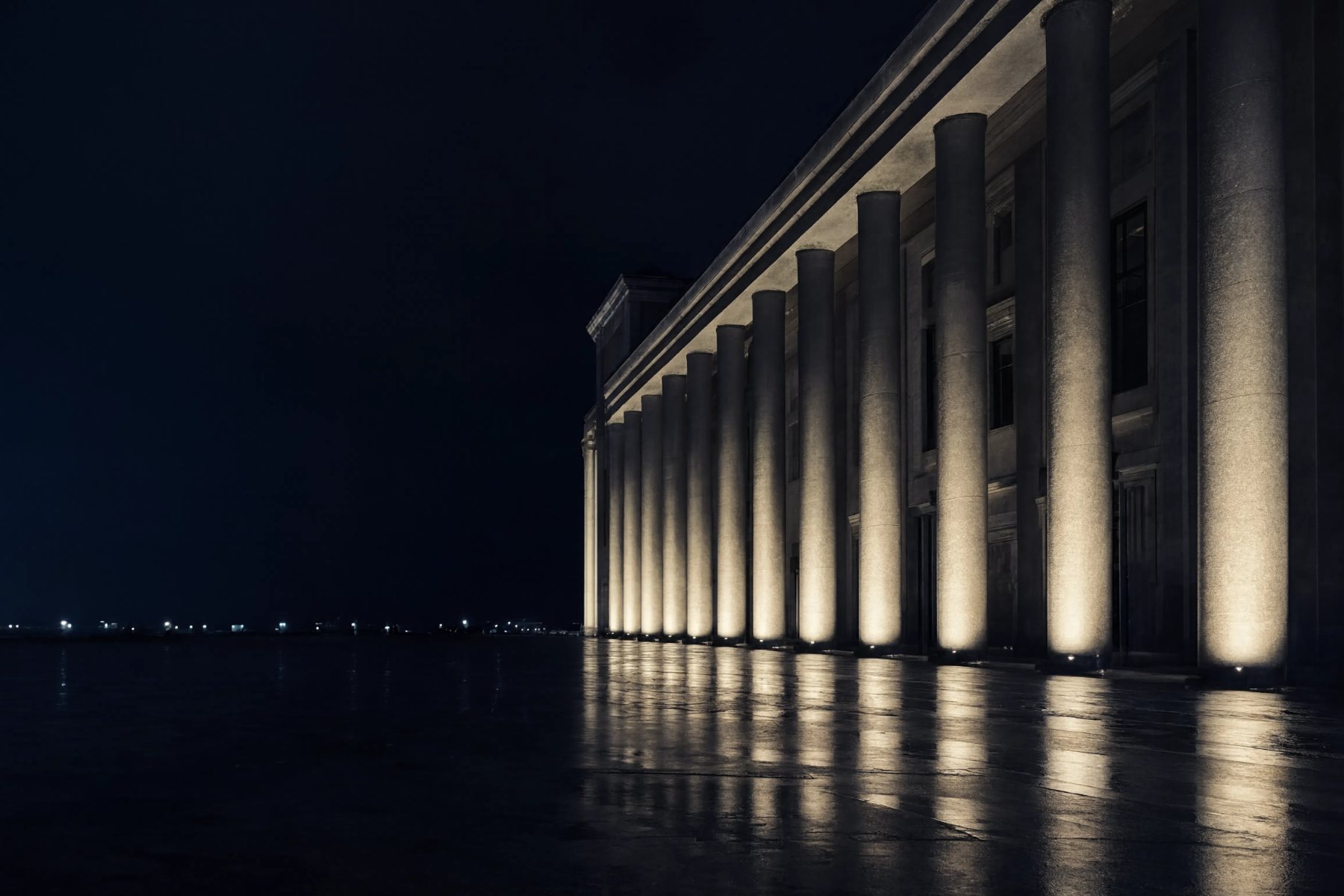 Illuminated colonnade of a public building at night, evoking regulation and legislation