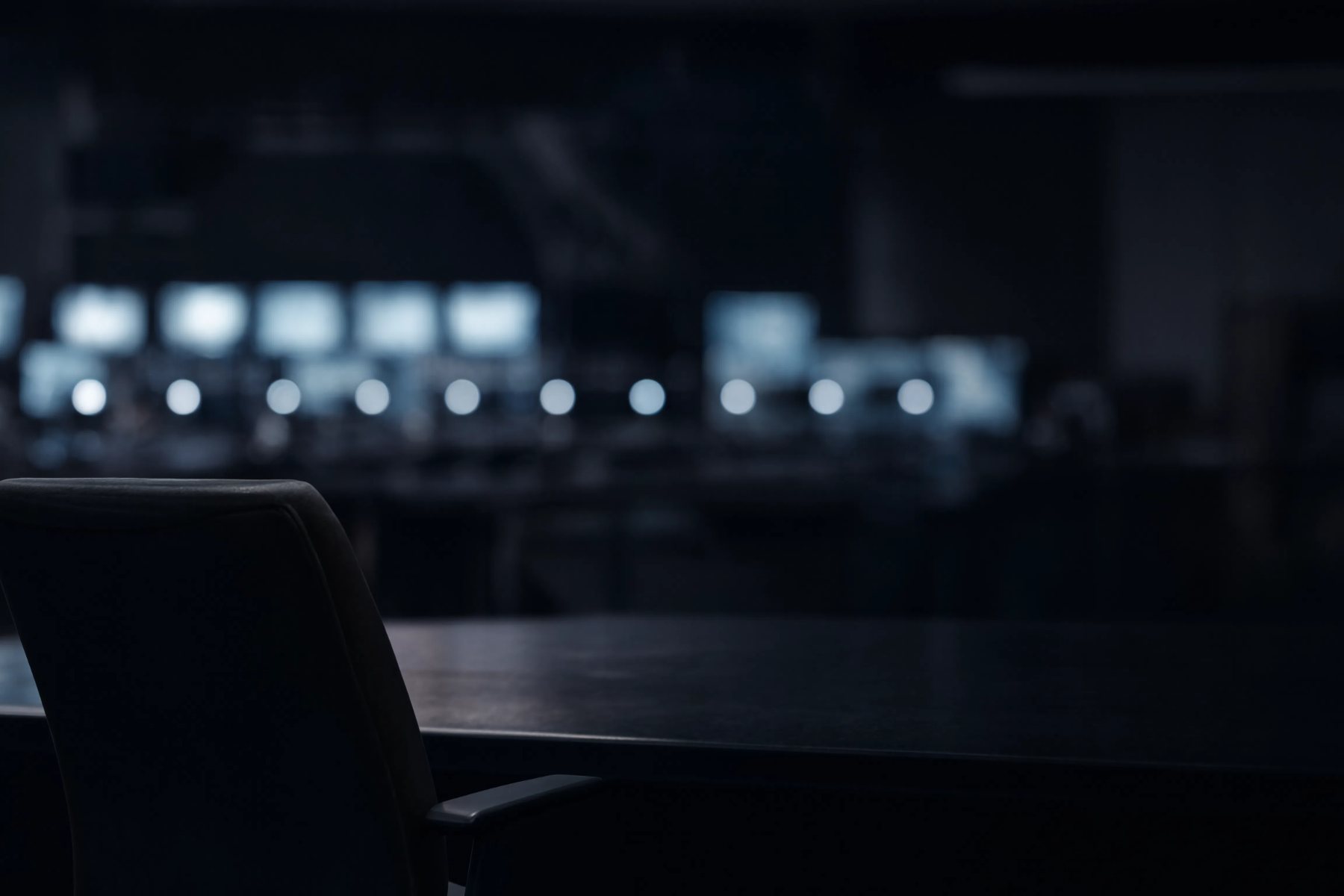 Sala de controle industrial à noite com monitores desfocados ao fundo