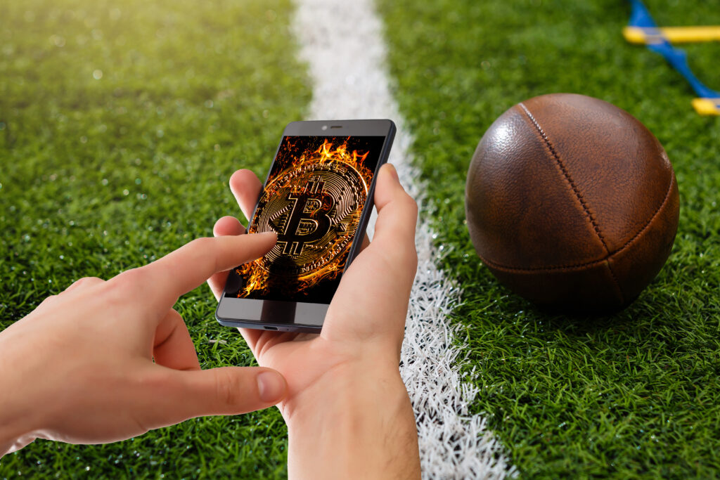 A man uses a phone to bet football using bitcoin