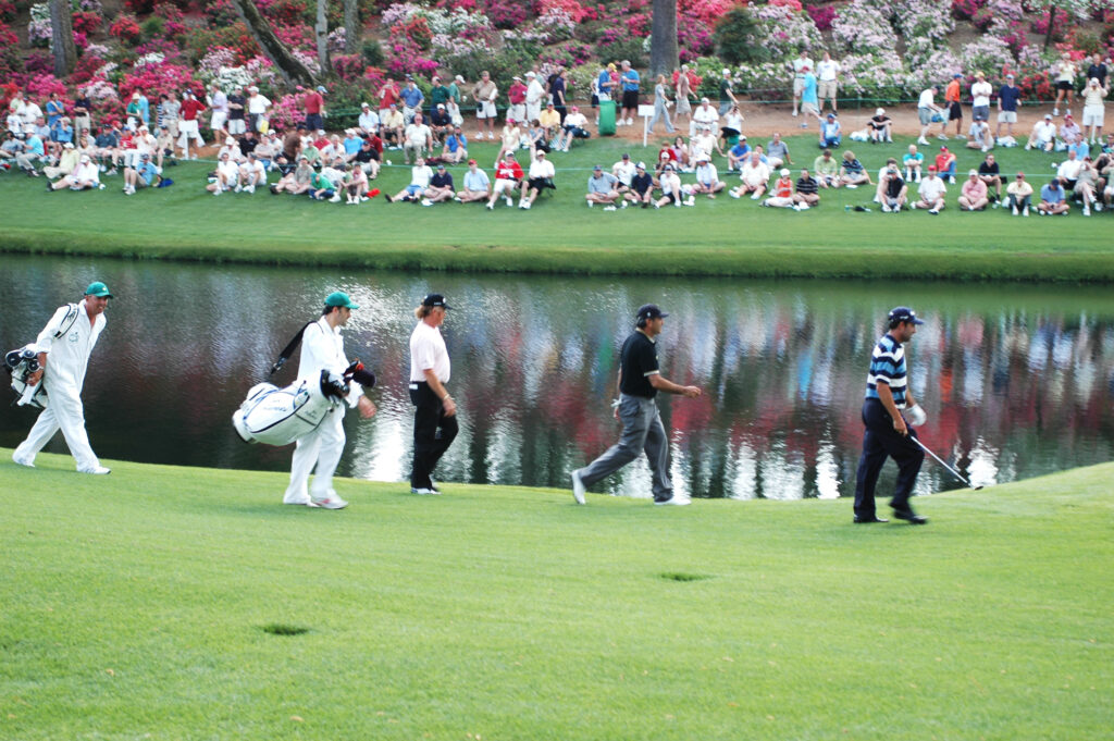 Players walk up a green in front of the gallery