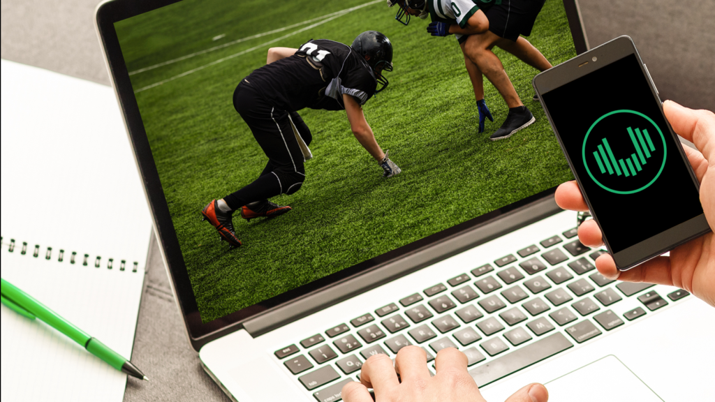 A person does Super Bowl prop betting on a phone while looking at a laptop