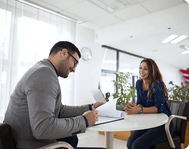 A public speaking coach reviewing paperwork with a client in a bright, modern office.