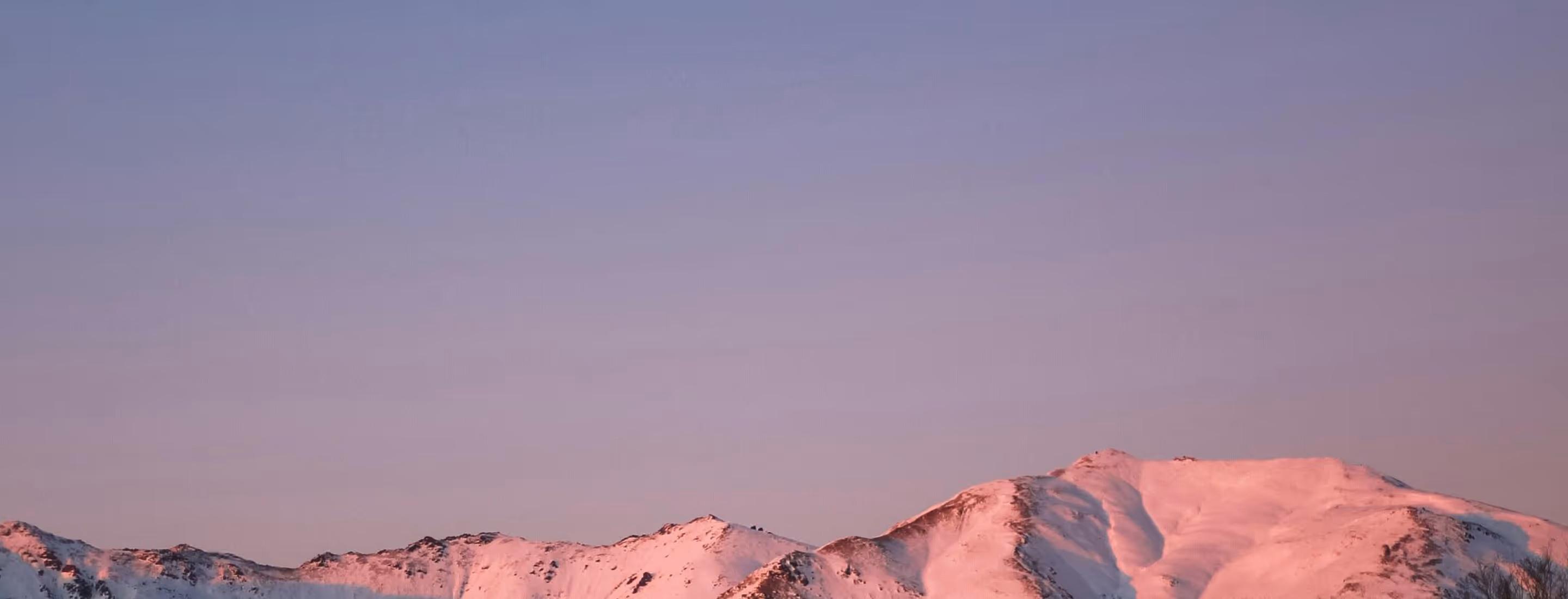 Snow-covered mountain peaks glowing pink in morning light