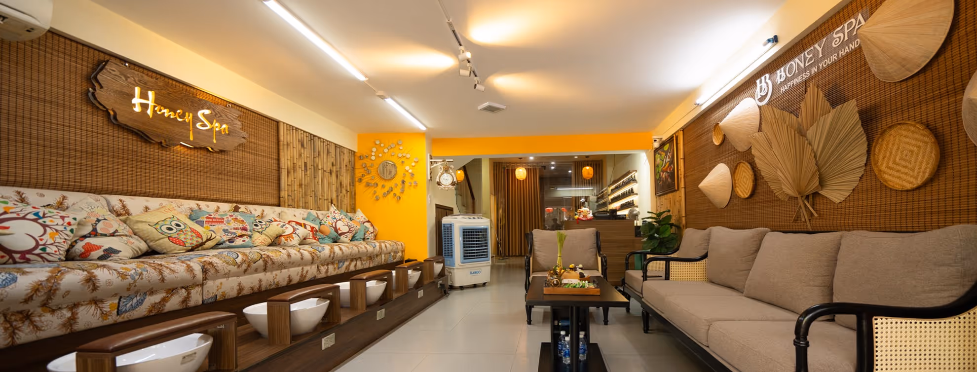 Cozy spa waiting area with cushioned benches, foot baths, decorative wall art, and calming lighting.