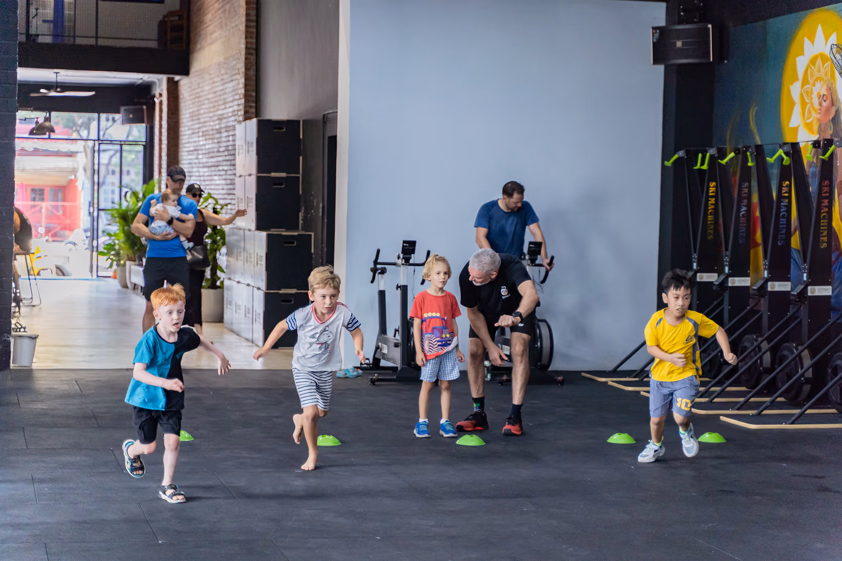 Children run across the gym while coaches supervise the group activity.