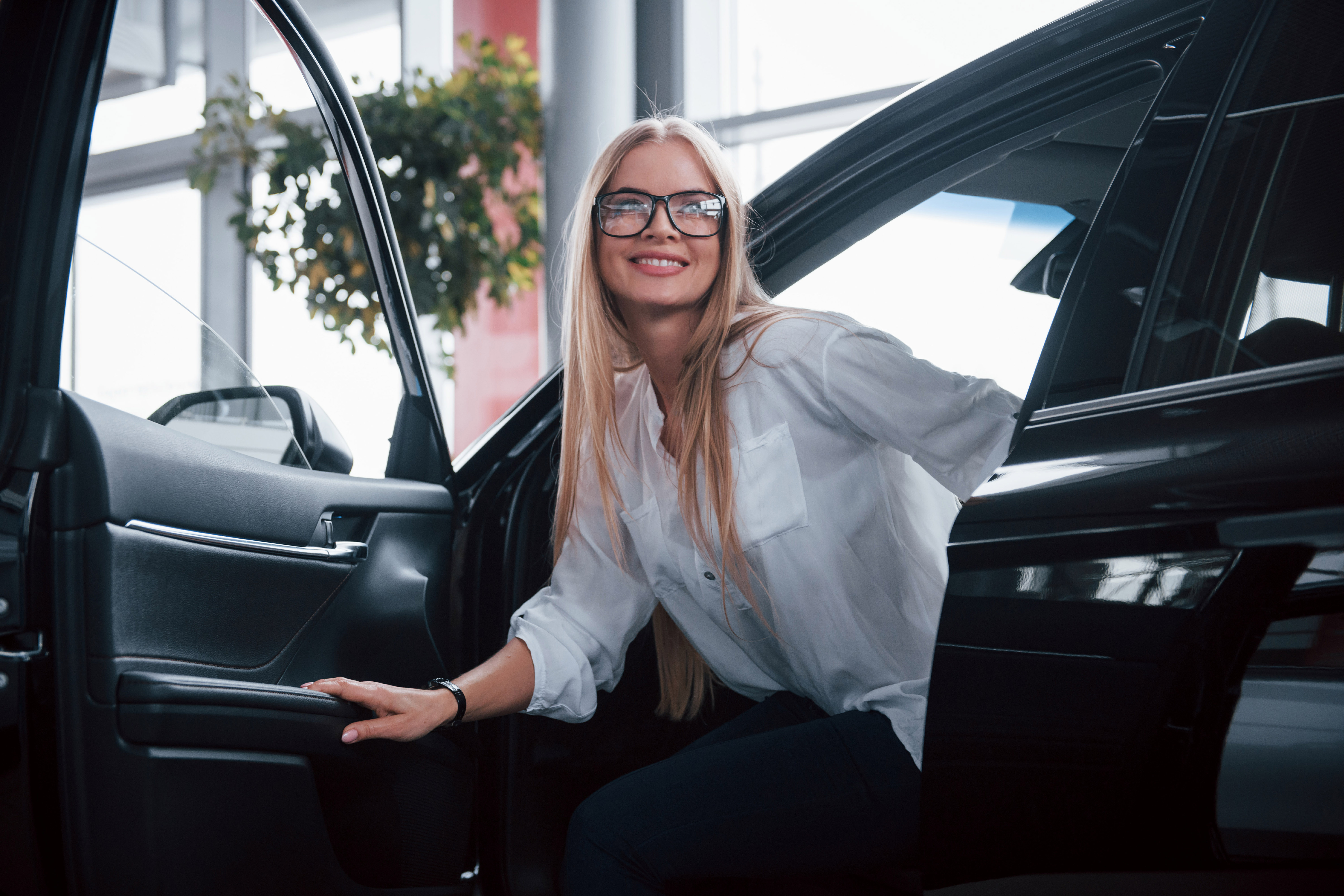 Woman exiting car at showroom car dealership