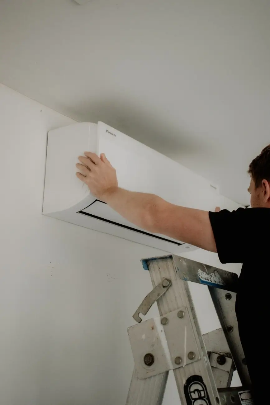 Image of technician installing a heat pump in a Papamoa home